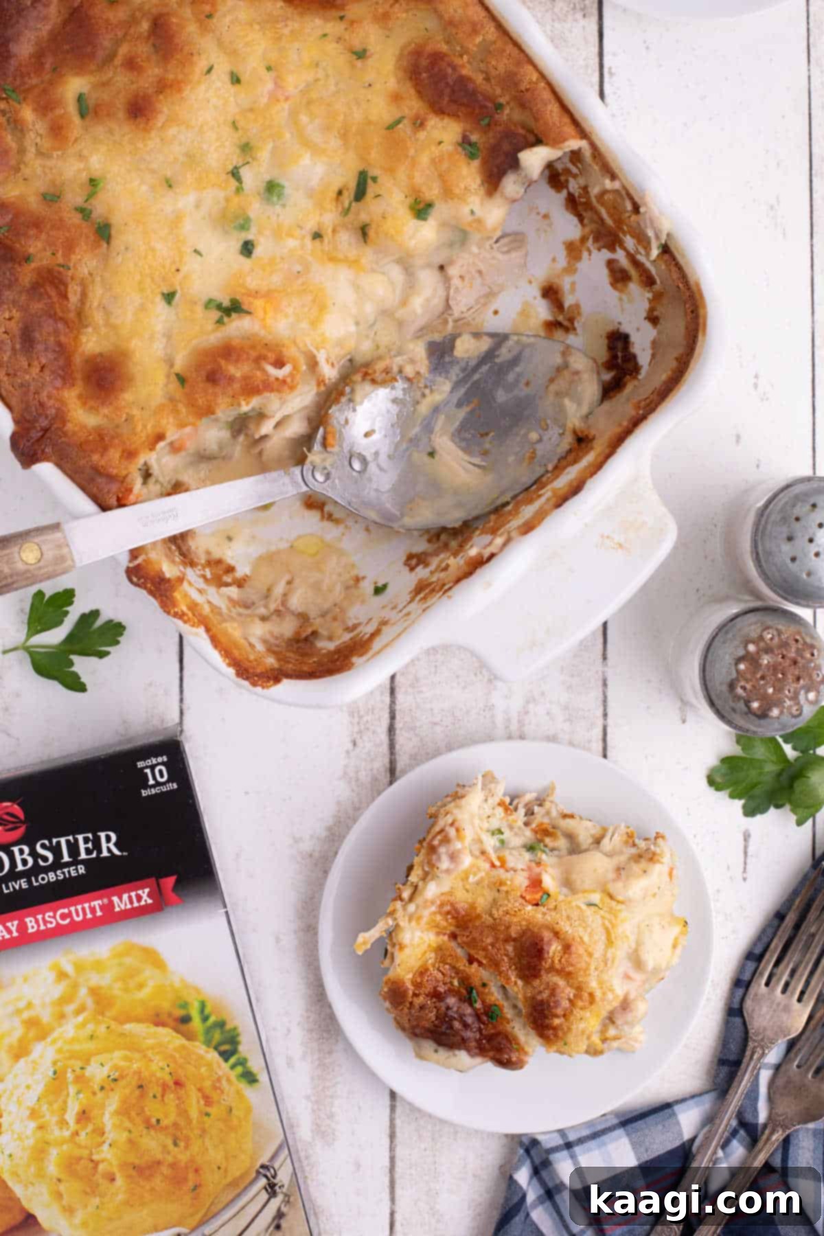Overhead shot of a casserole dish with a chicken cobbler recipe inside, made with red lobster biscuit mix, with a serving already dished onto a plate beside it.