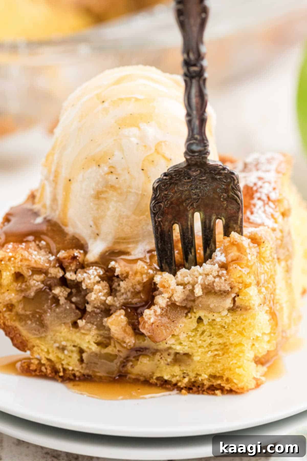 Close up shot of a piece of apple pie cake with a fork digging into the soft cake and apple filling.