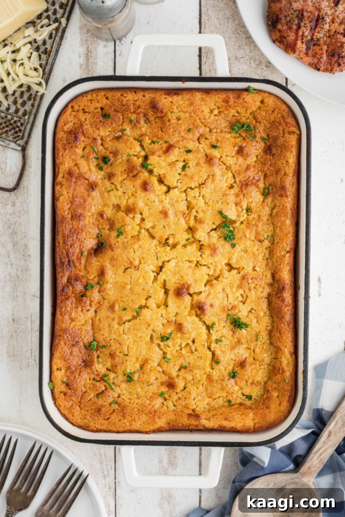 Overhead view of a dish of cornbread pudding, golden brown and steaming slightly.