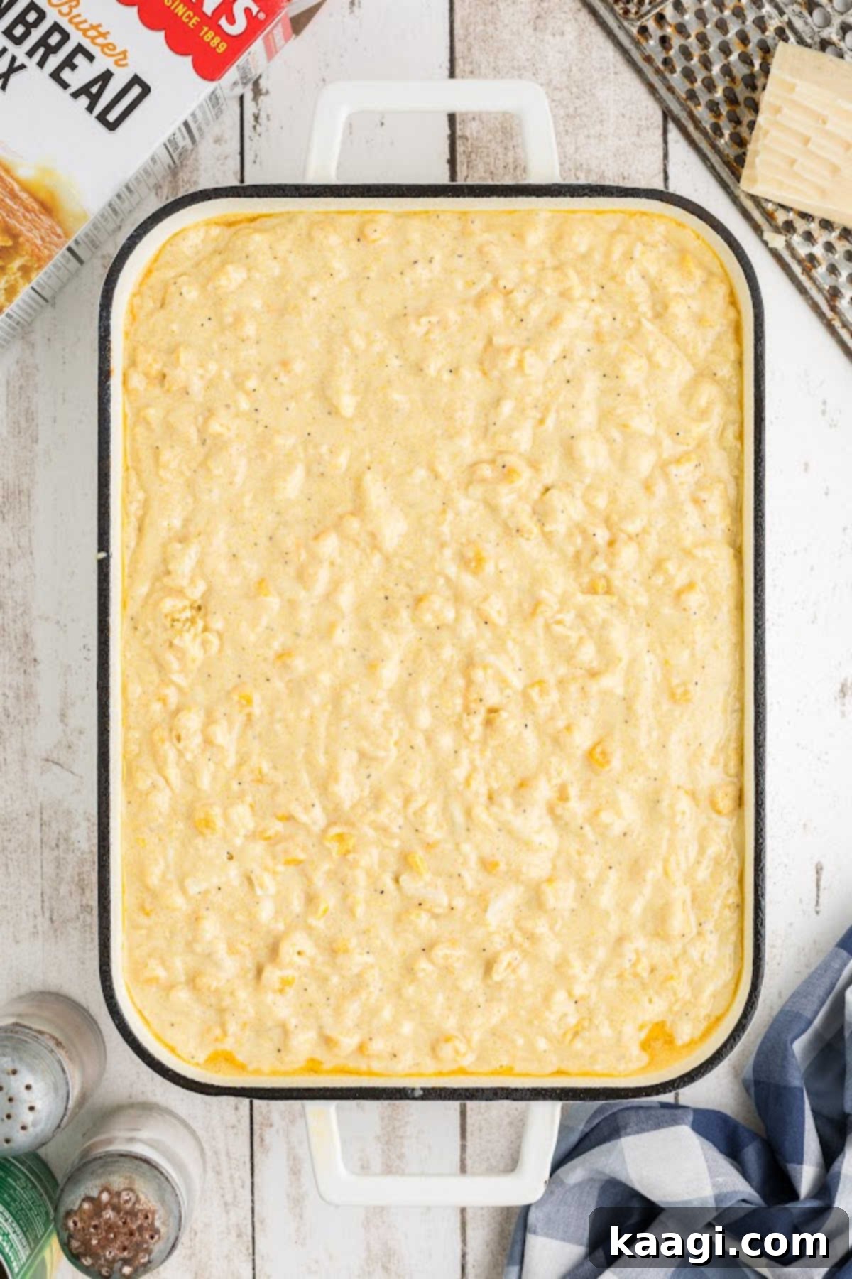 Cornbread pudding batter poured into a greased casserole dish, ready for baking in the oven.