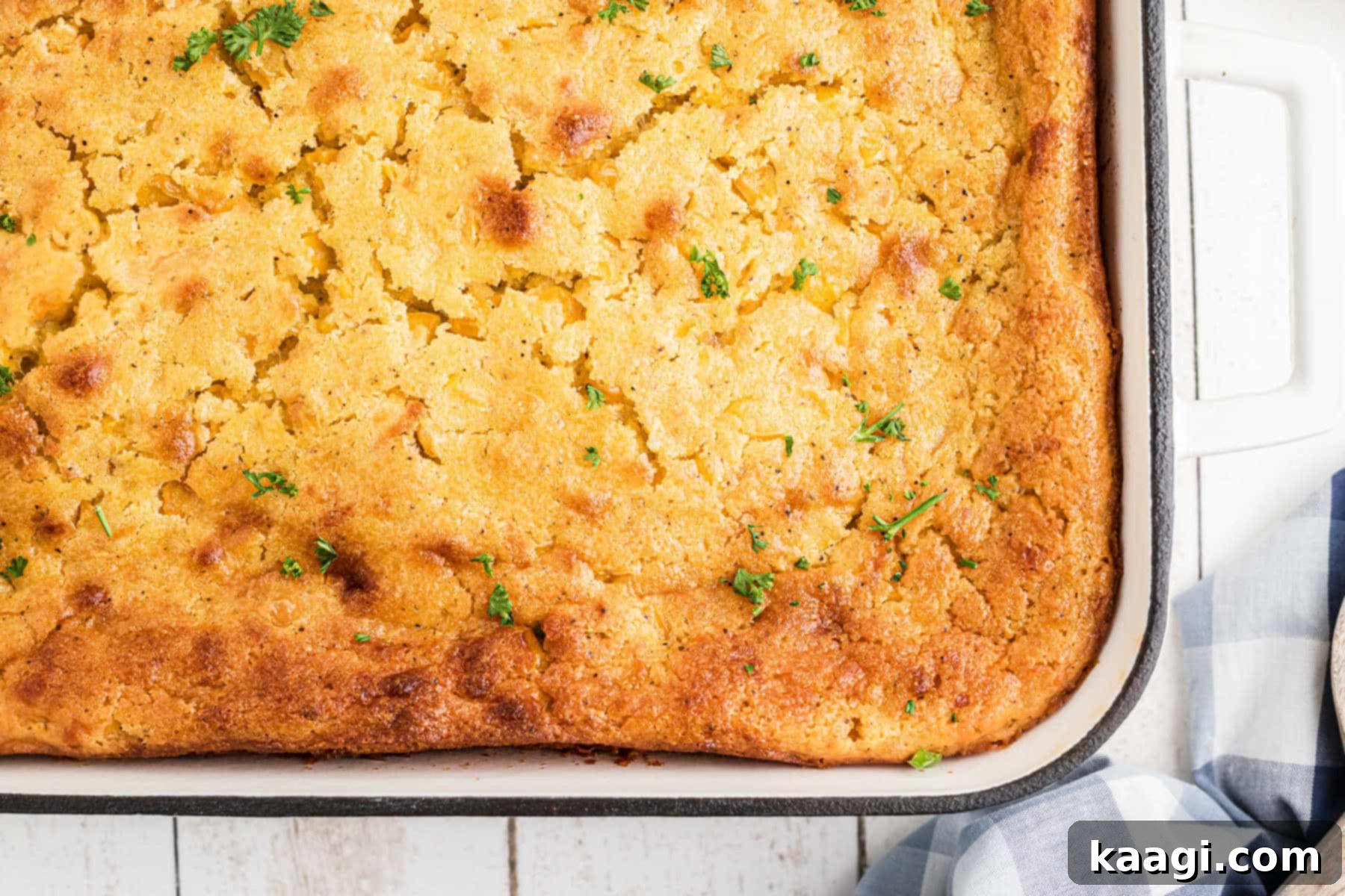 Overhead shot of a delicious, golden-brown cornbread pudding fresh out of the oven, just the corner visible.