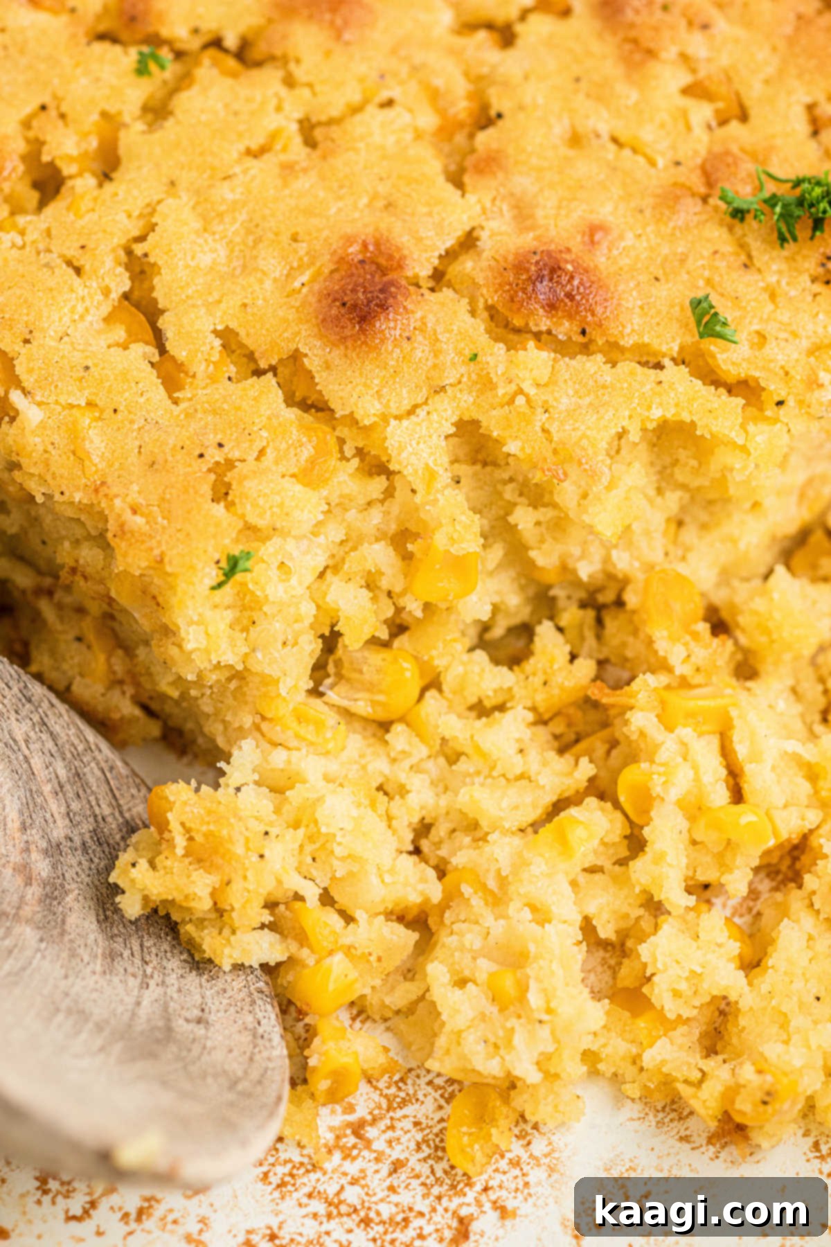 Close up view of a rich, creamy cornbread pudding in a casserole dish, highlighting its texture.
