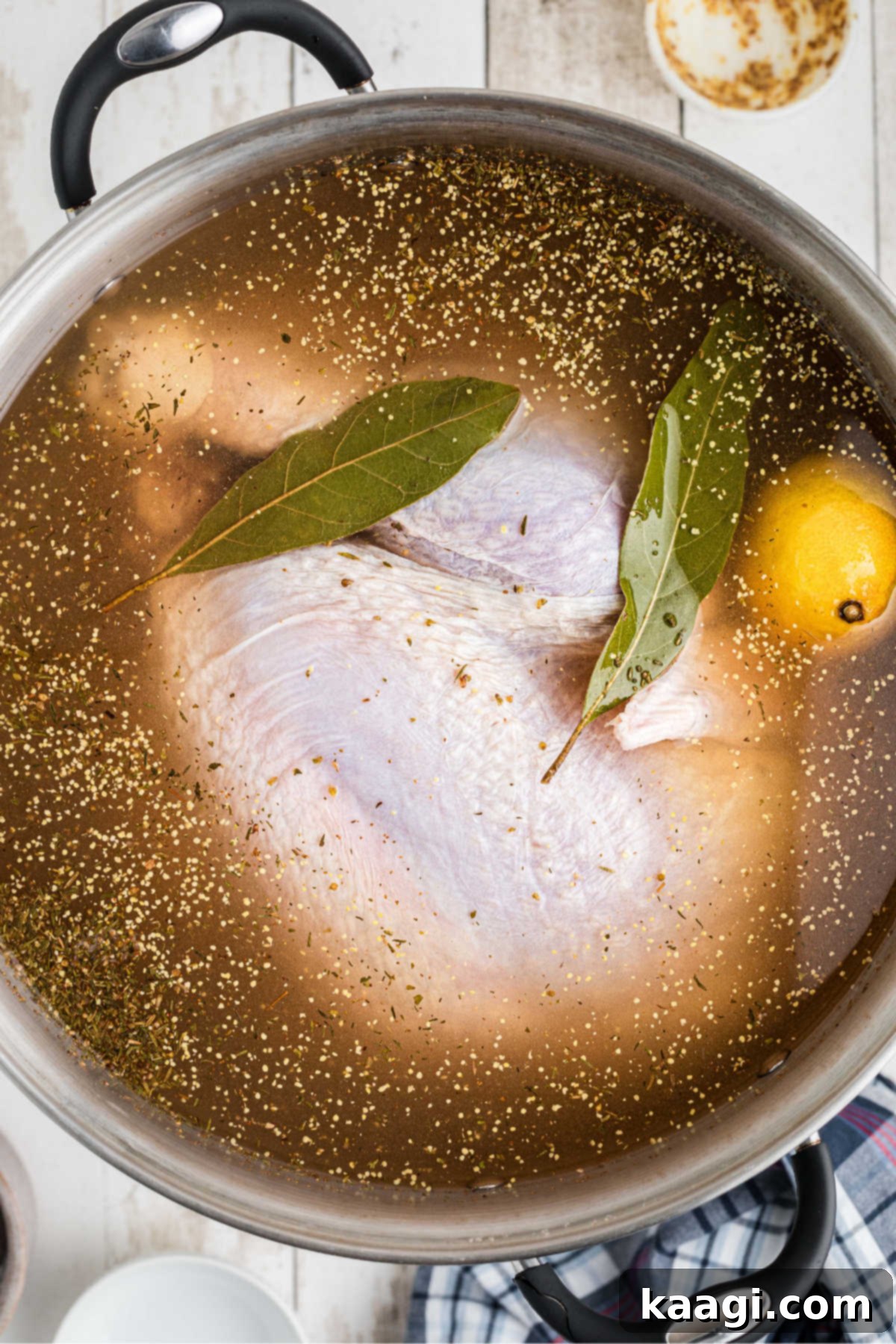 Crisp and Juicy Turkey Triumph 4 A large turkey soaking in a brine solution with bay leaves, seasonings, and lemon slices.