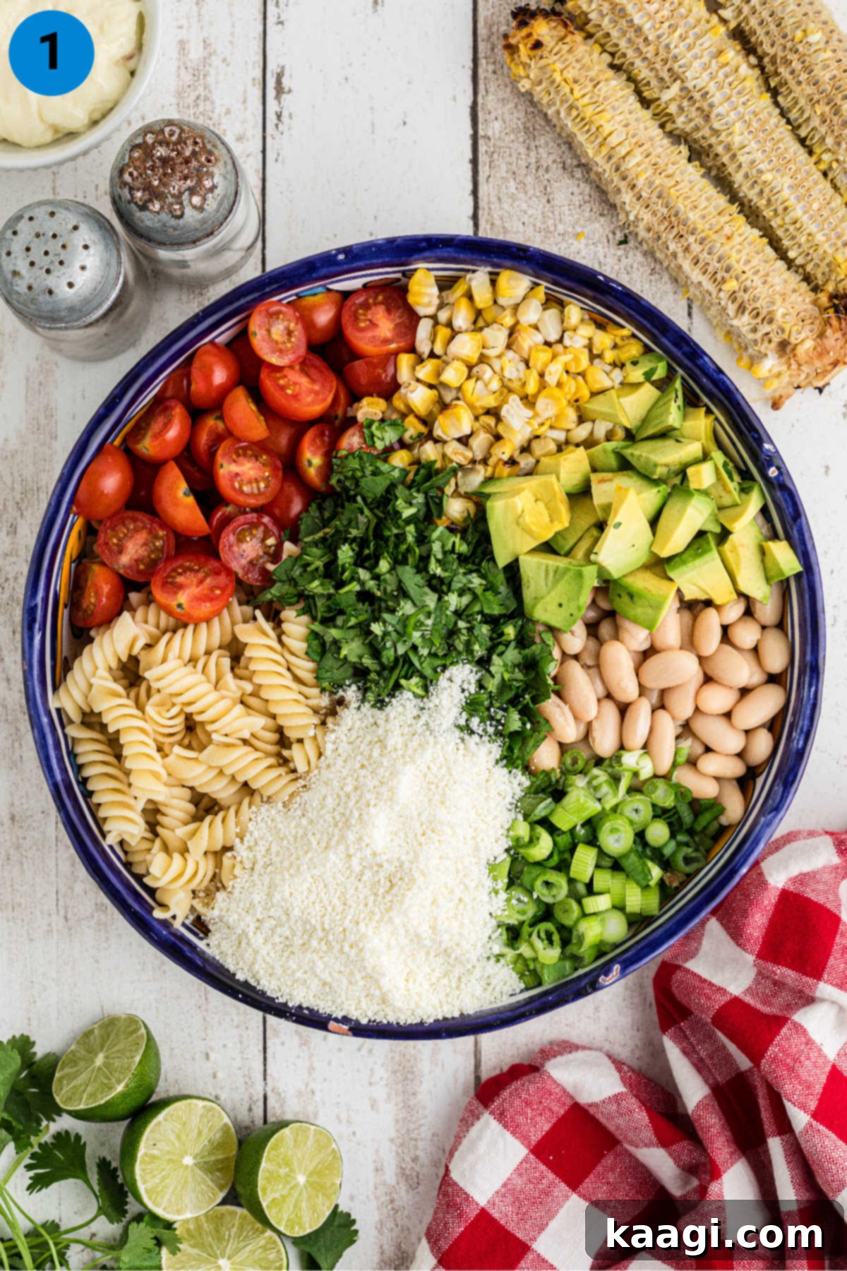 Ingredients needed to make Elotes pasta salad, freshly chopped and laid out in a large mixing bowl.