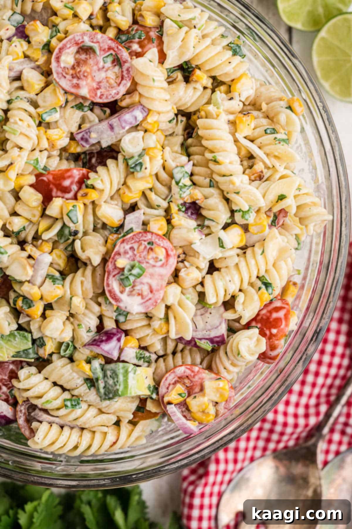 Overhead side shot of a bowl of cilantro lime pasta salad, garnished with fresh cilantro and lime wedges.
