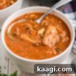 A bowl of Louisiana turtle soup with a spoon digging in, garnished with parsley, cropped square.