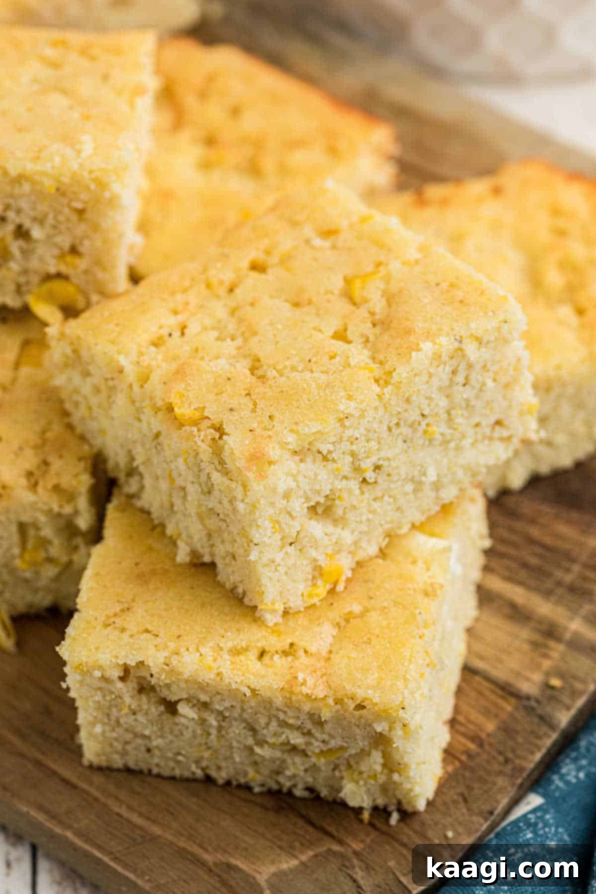 Two pieces stacked of golden-brown sour cream cornbread, showcasing its moist texture.