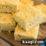 A few square pieces of sour cream cornbread on a wooden board.