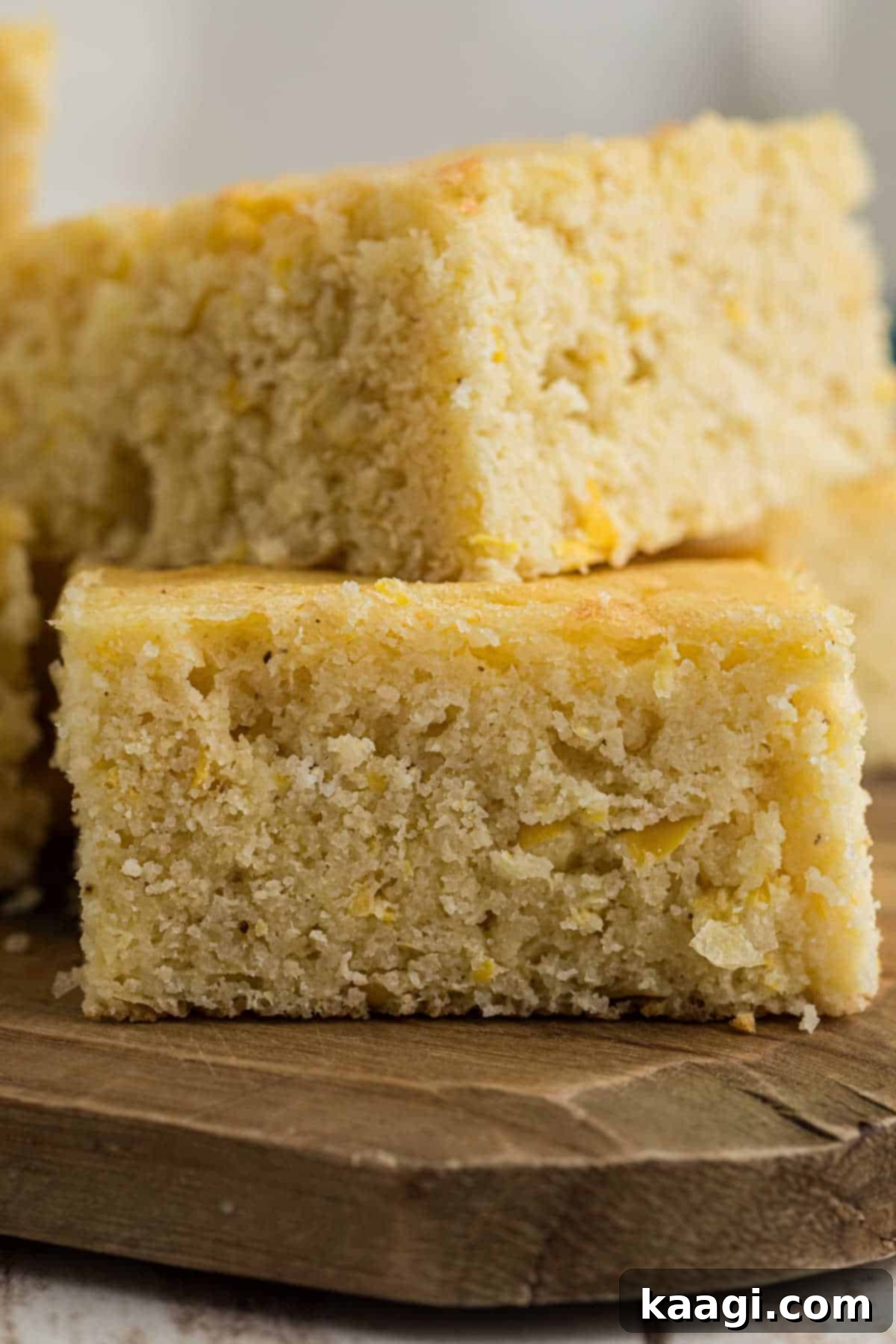 Close up picture of two pieces of square sour cream cornbread, showing its inviting texture.
