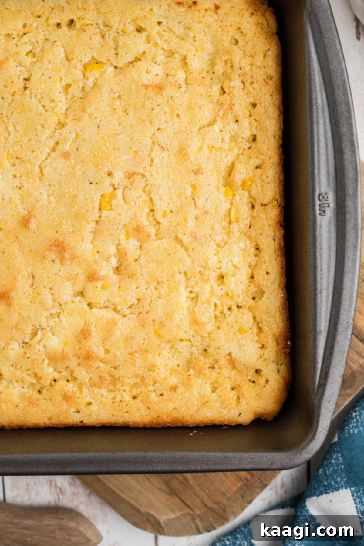 OVerhead shot of the corner of a cornbread in a pan, emphasizing its crispy edges and soft interior.