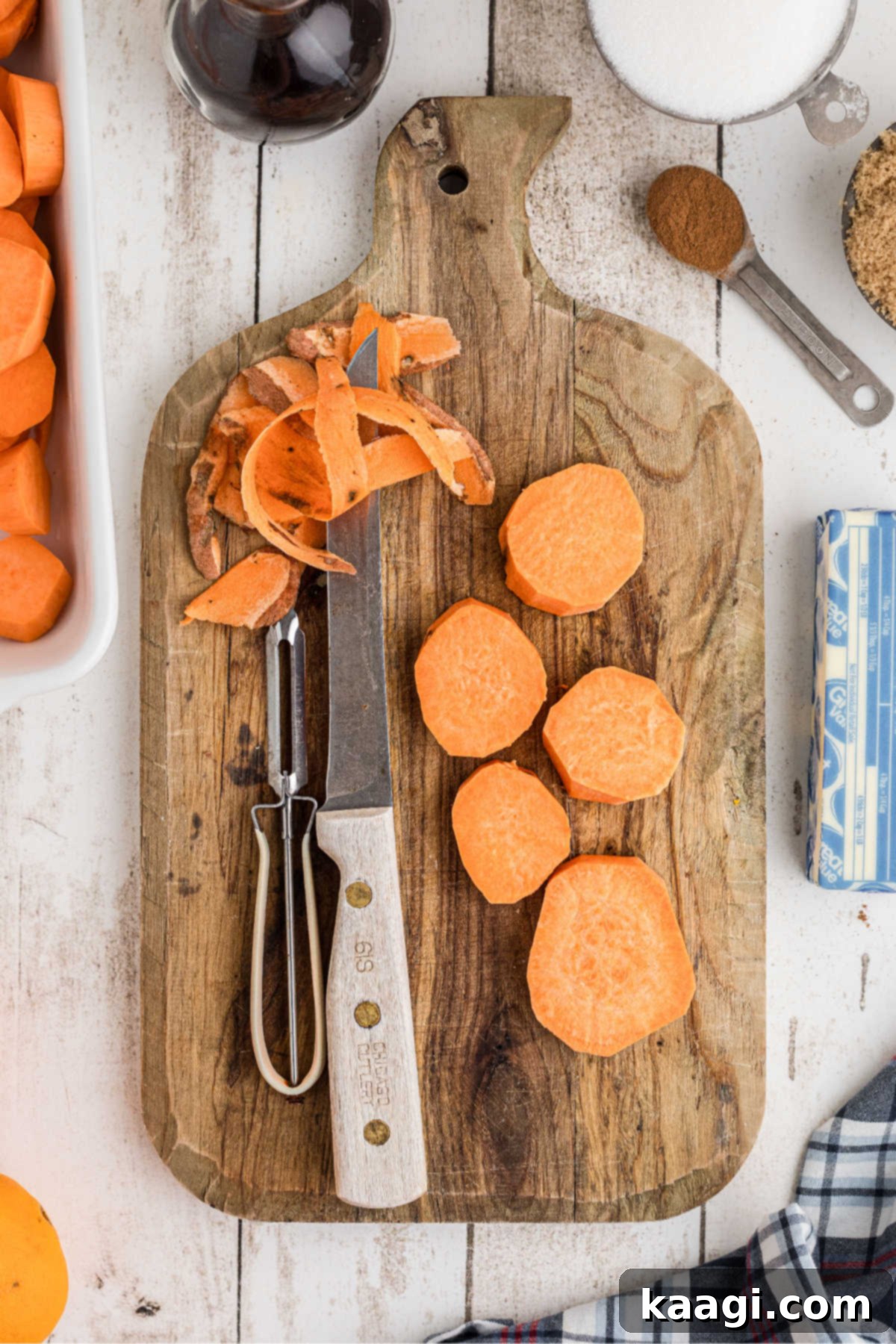 A cutting board with some yams being peeled and sliced.