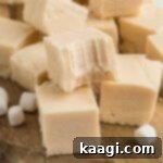 A pile of vanilla fudge with one having a bite taken out, emphasizing its texture.