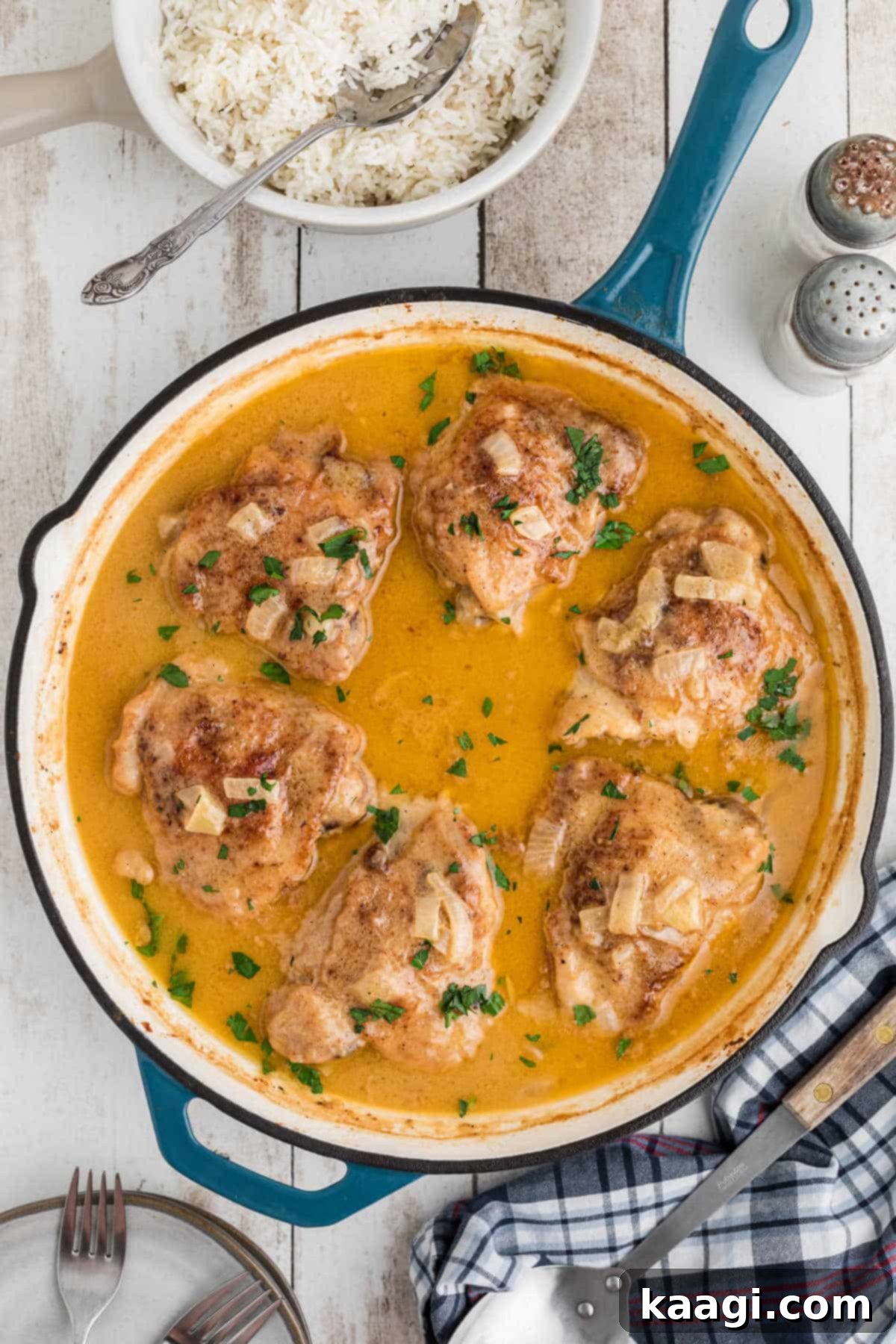 Overhead shot of a skillet full of golden-brown smothered chicken with a creamy gravy, garnished with fresh herbs.