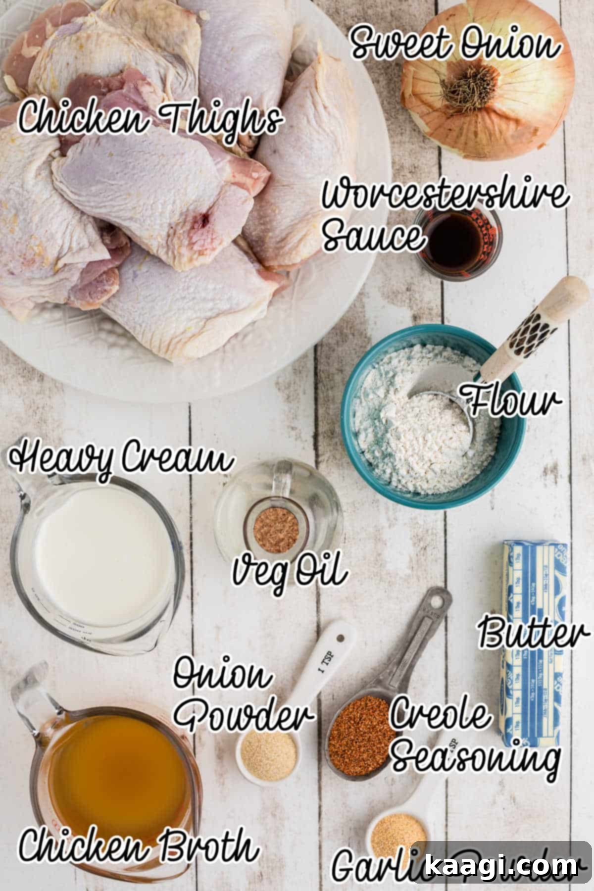 Overhead view of fresh ingredients neatly arranged on a counter, including flour, various spices, chicken thighs, onions, butter, and liquids, ready to make smothered chicken.