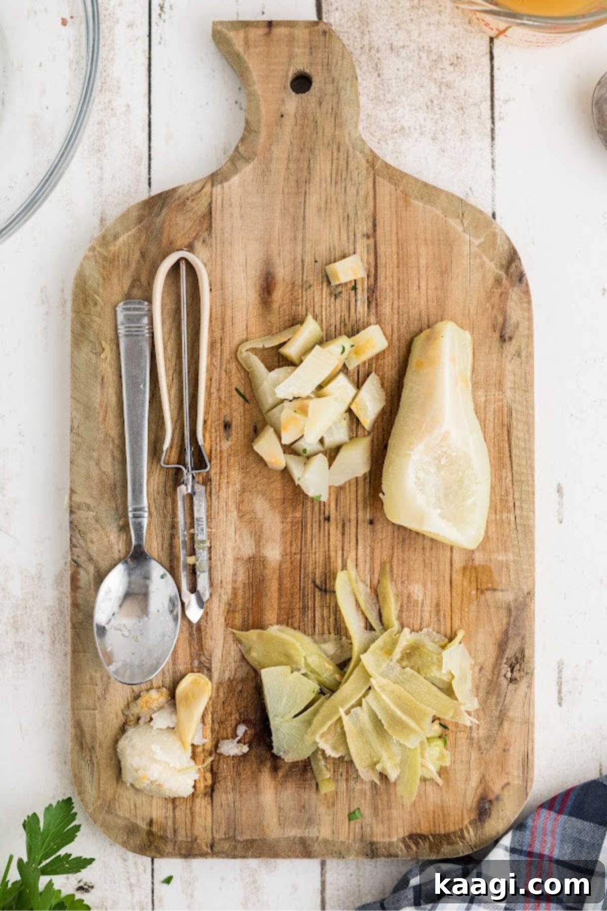Cooked mirlitons being peeled, deseeded, and chopped into chunks on a cutting board.