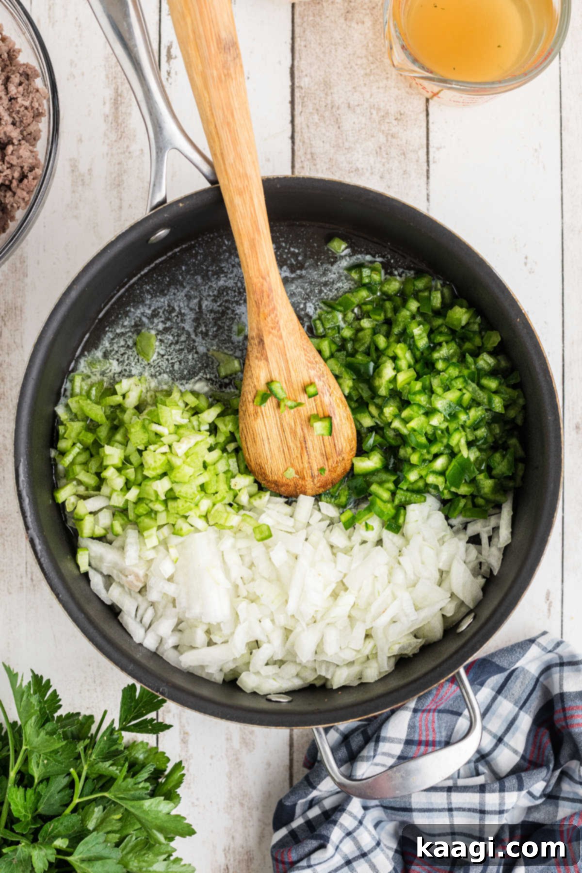 Diced onions, bell pepper, and celery cooking in butter in a skillet.