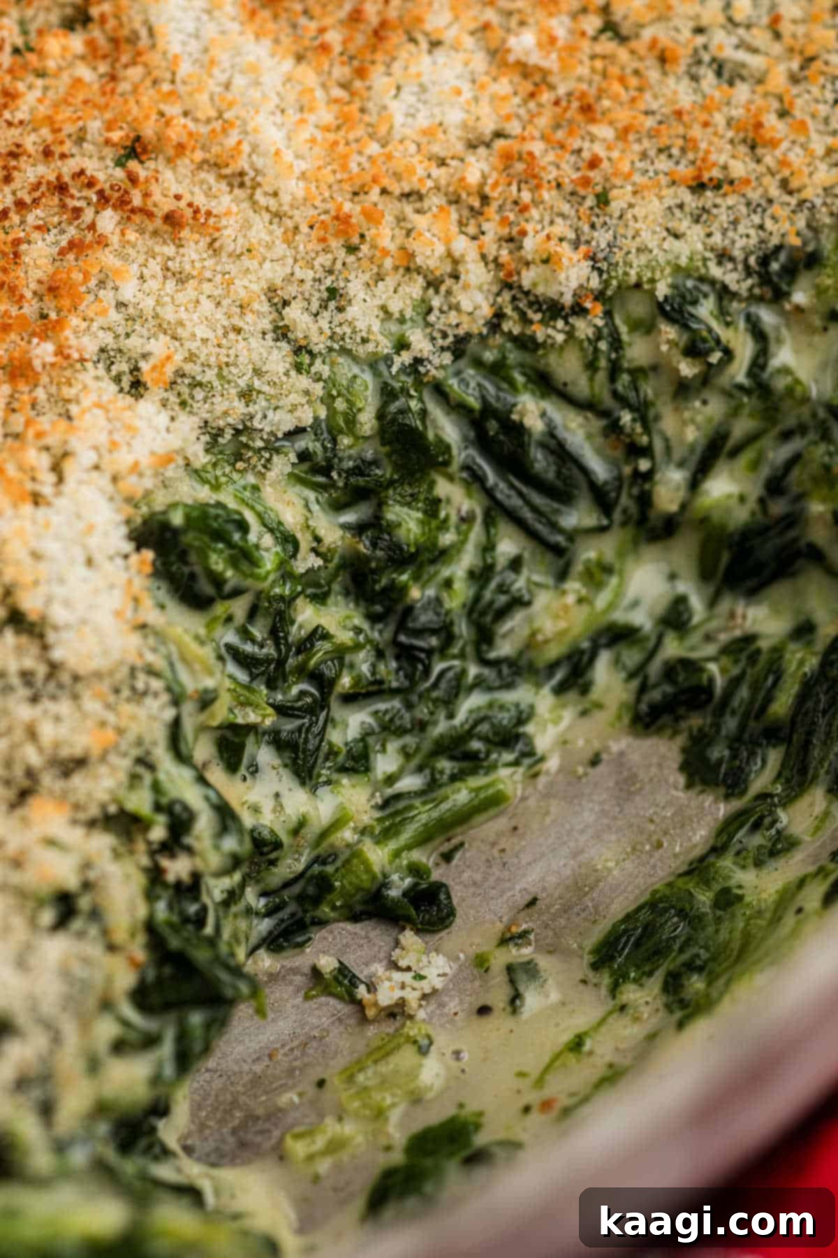 Very close up shot of a spinach madeleine dish, looking incredibly cheesy and creamy with a golden crust.