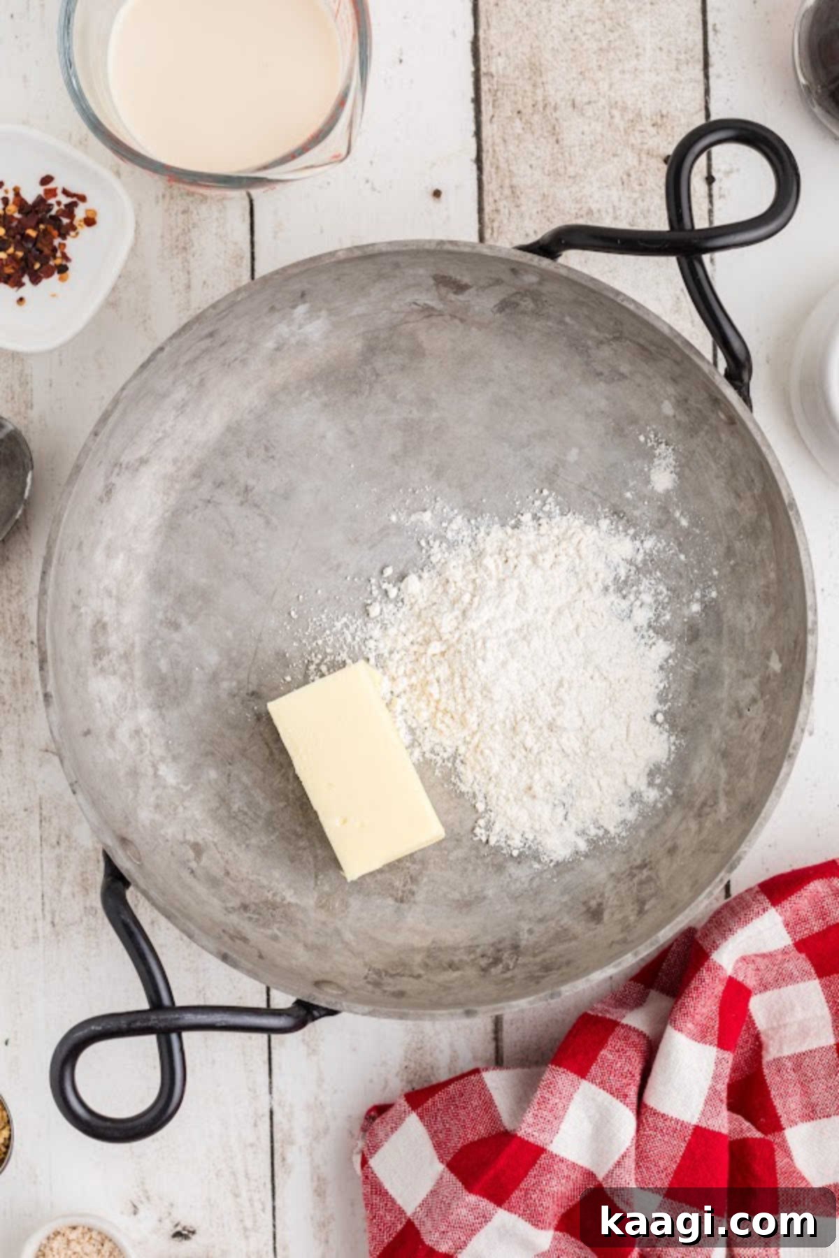 Butter melting and flour being added to a skillet to create a roux.
