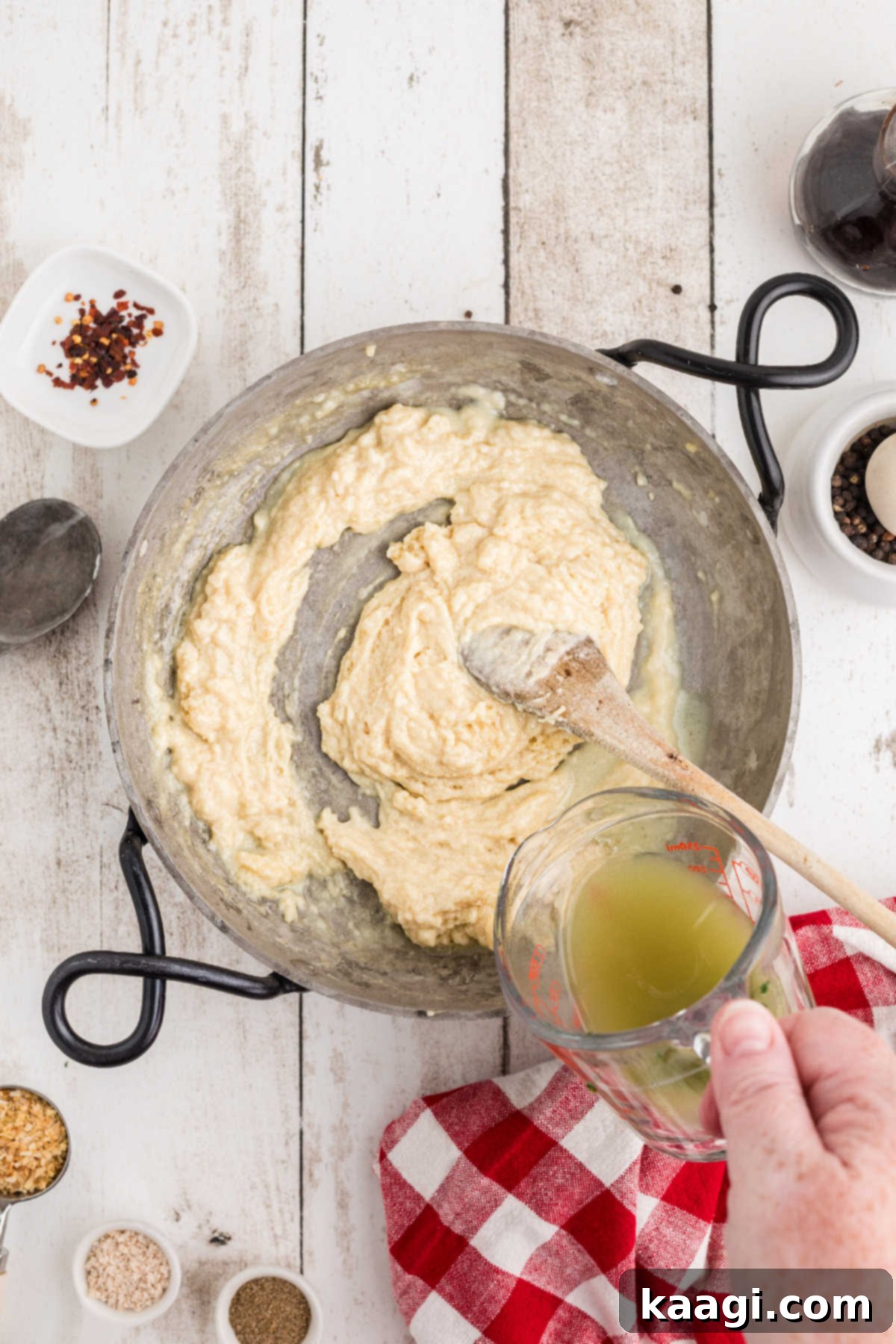 Reserved spinach liquor being poured into the roux and milk mixture.