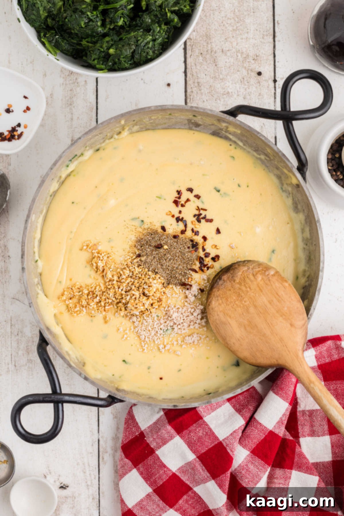 Seasonings being stirred into the melted cheese sauce in a skillet.