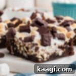 A very close-up, tempting shot of a perfectly cut rocky road brownie slice resting on a sleek granite plate, showcasing its rich fudgy texture, melted marshmallows, and crunchy nut pieces.