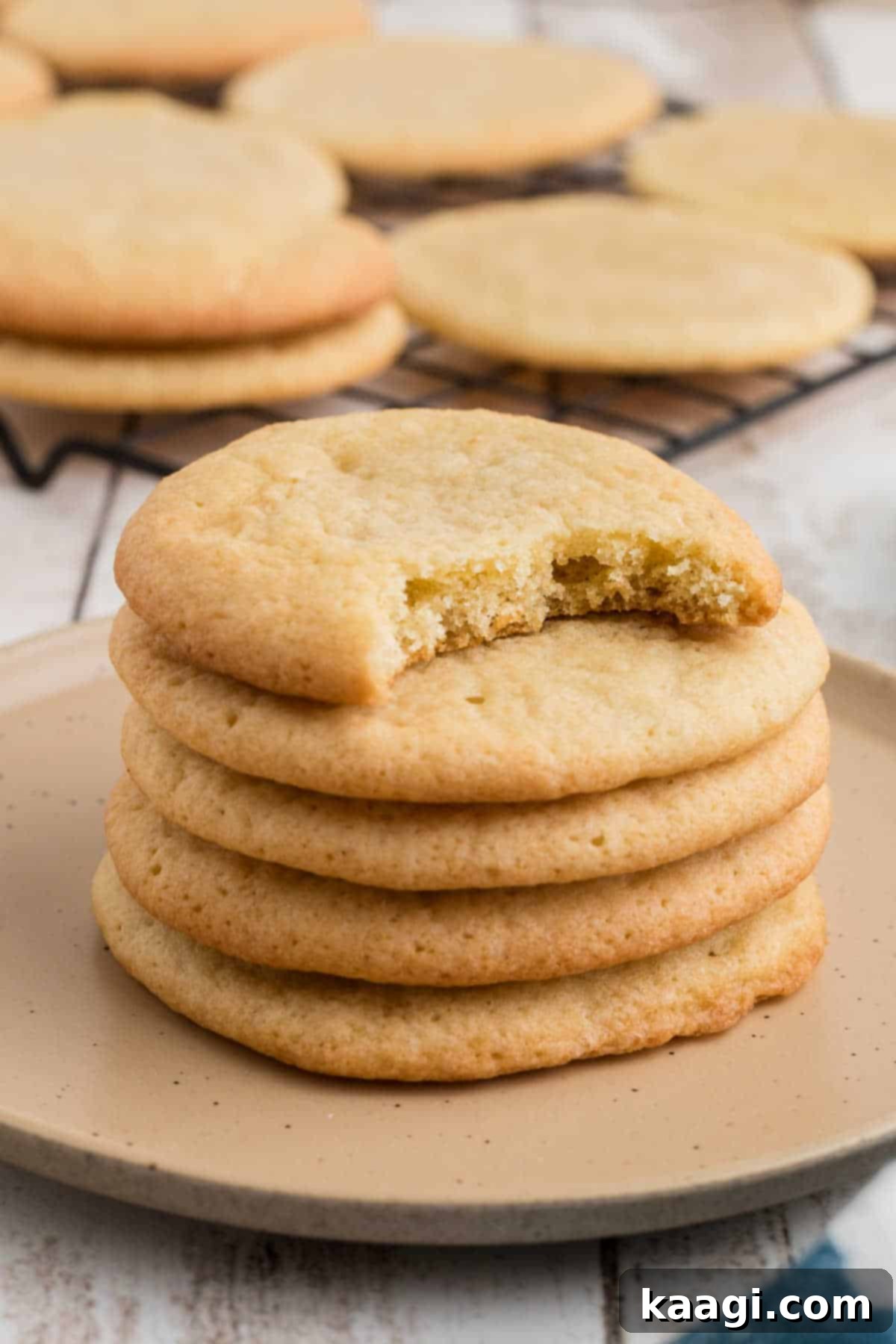 A stack of southern tea cakes, with the top one having a bite missing, showcasing their soft, buttery texture.