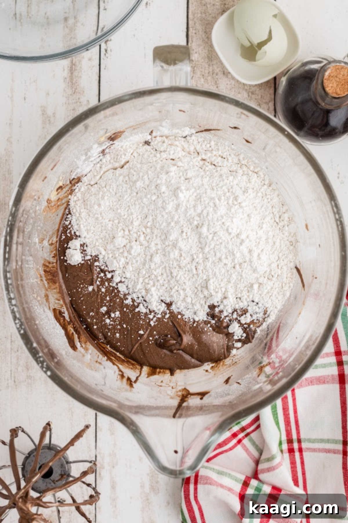 A flour mixture being added to a mixing bowl with a chocolate mixture.