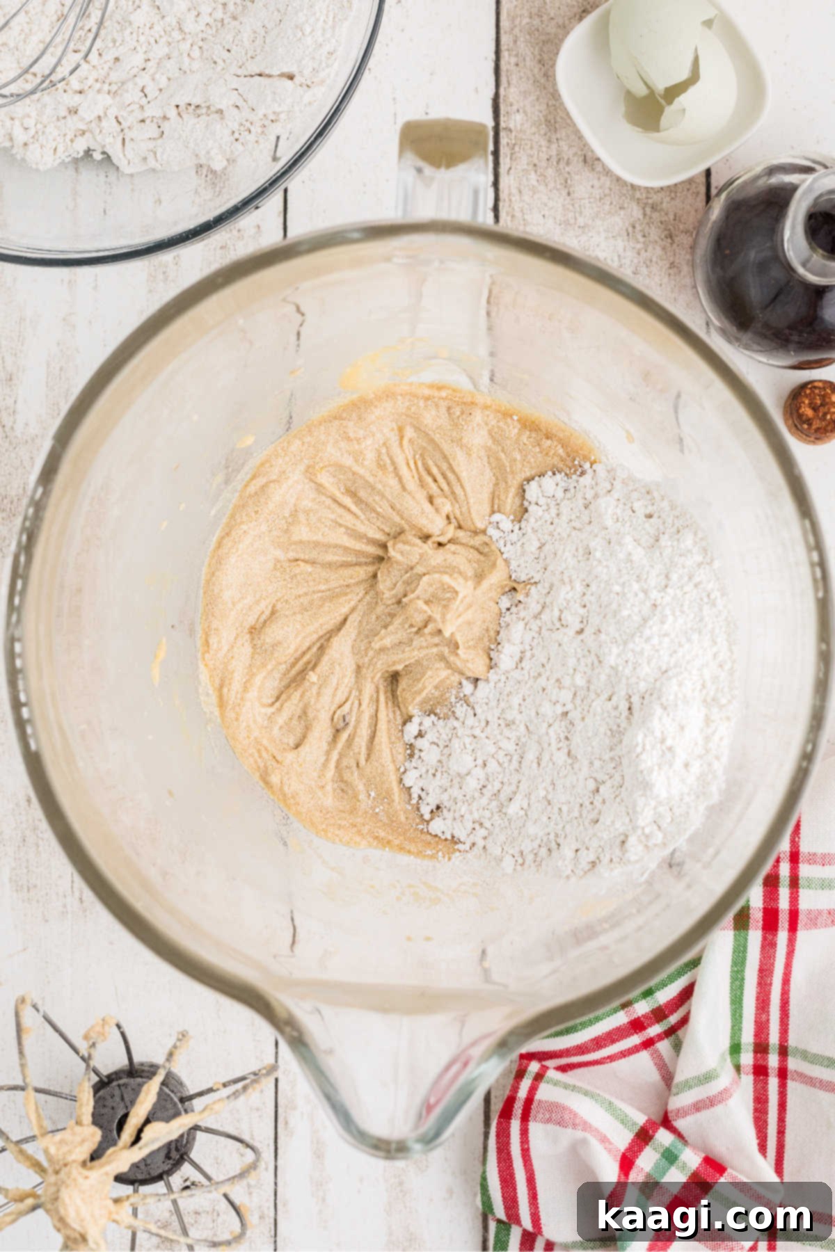 Flour mixture being added to a mixing bowl with sugar mixture.