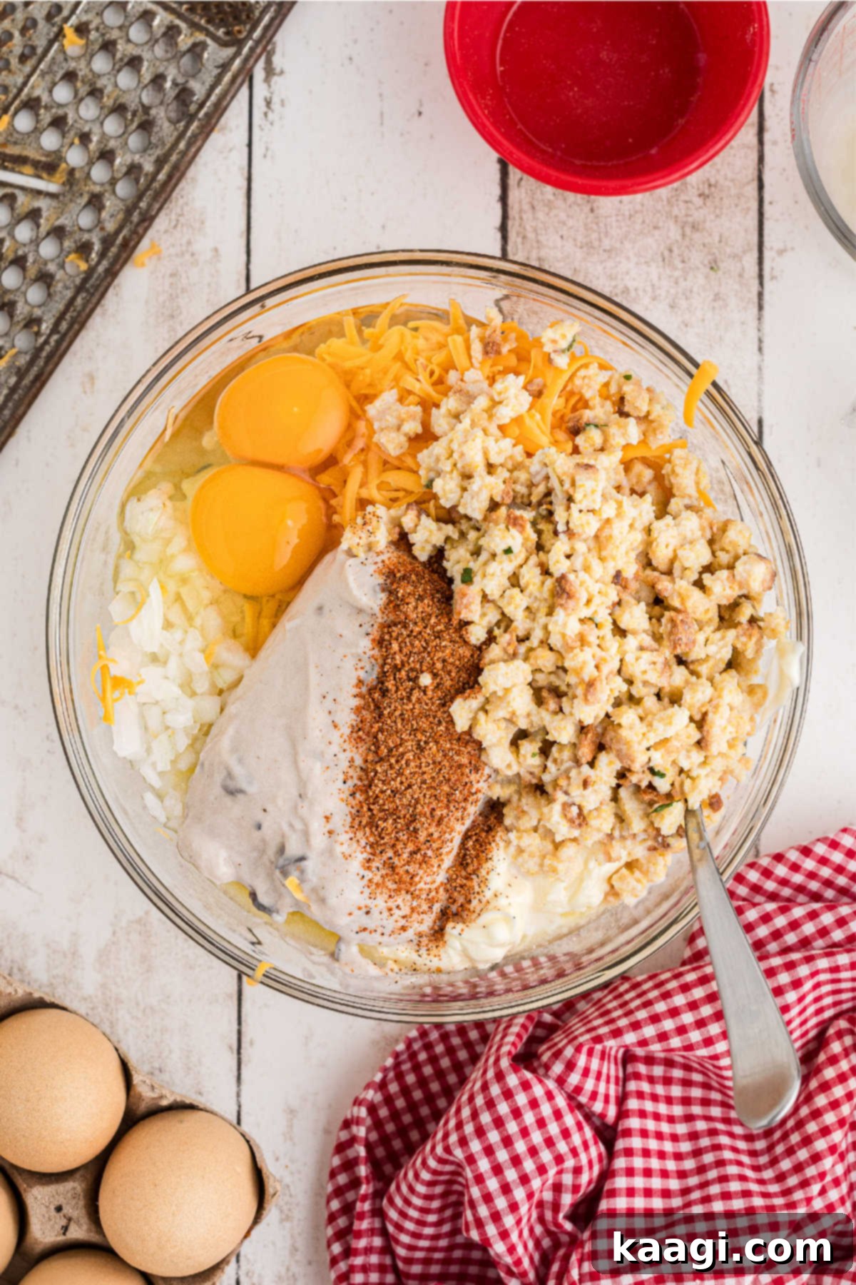 A large mixing bowl filled with the creamy base ingredients for the casserole, including stuffing mix, eggs, and cheese.