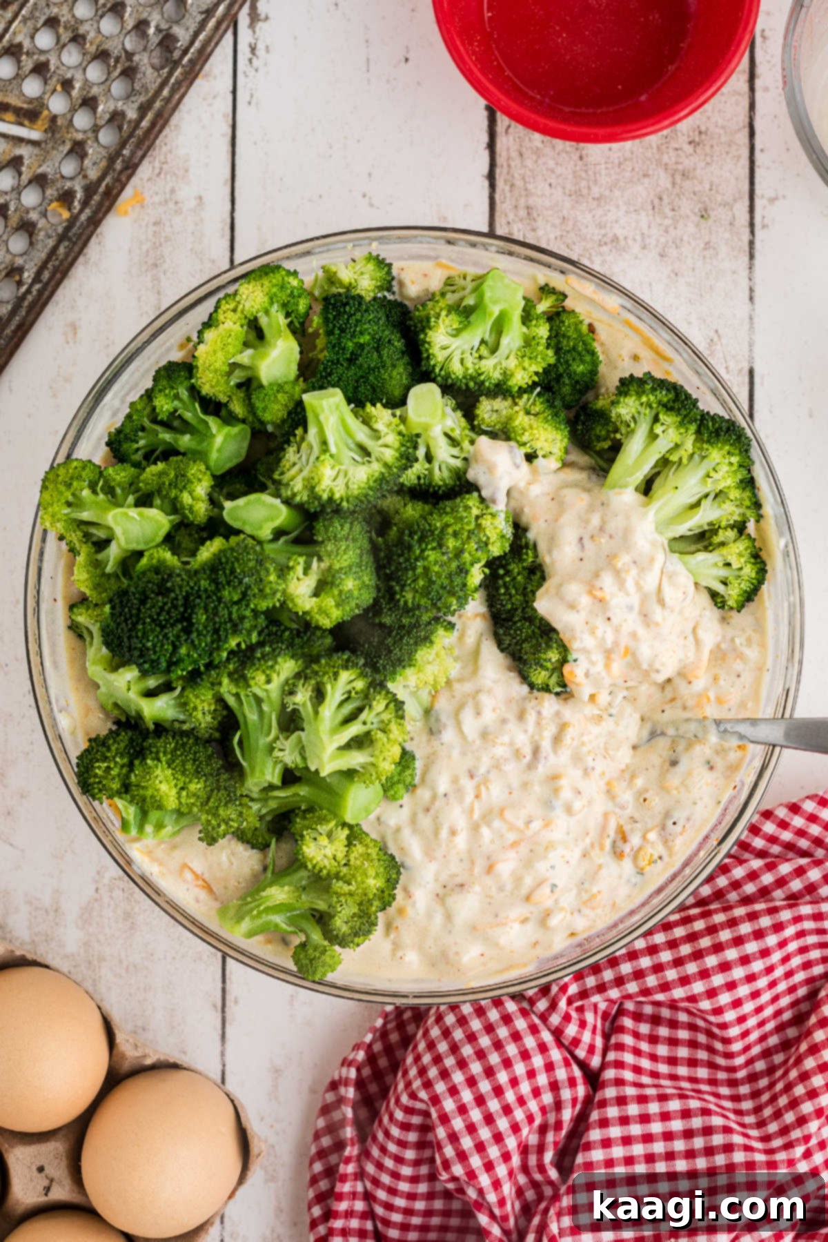 Golden Broccoli Bake 7 Steamed broccoli florets being gently folded into the creamy casserole mixture in a large mixing bowl.