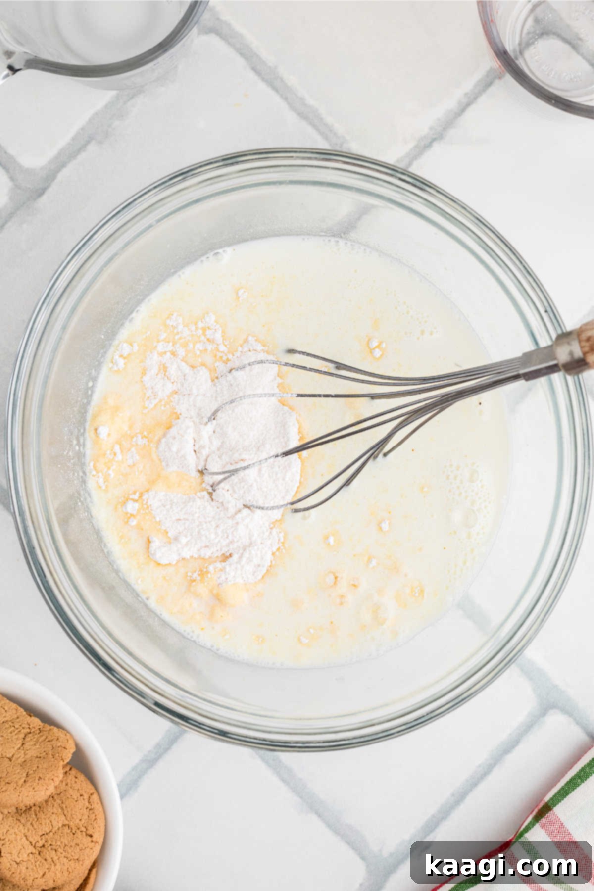 Pudding mix and cold milk in a glass mixing bowl, about to be whisked together.
