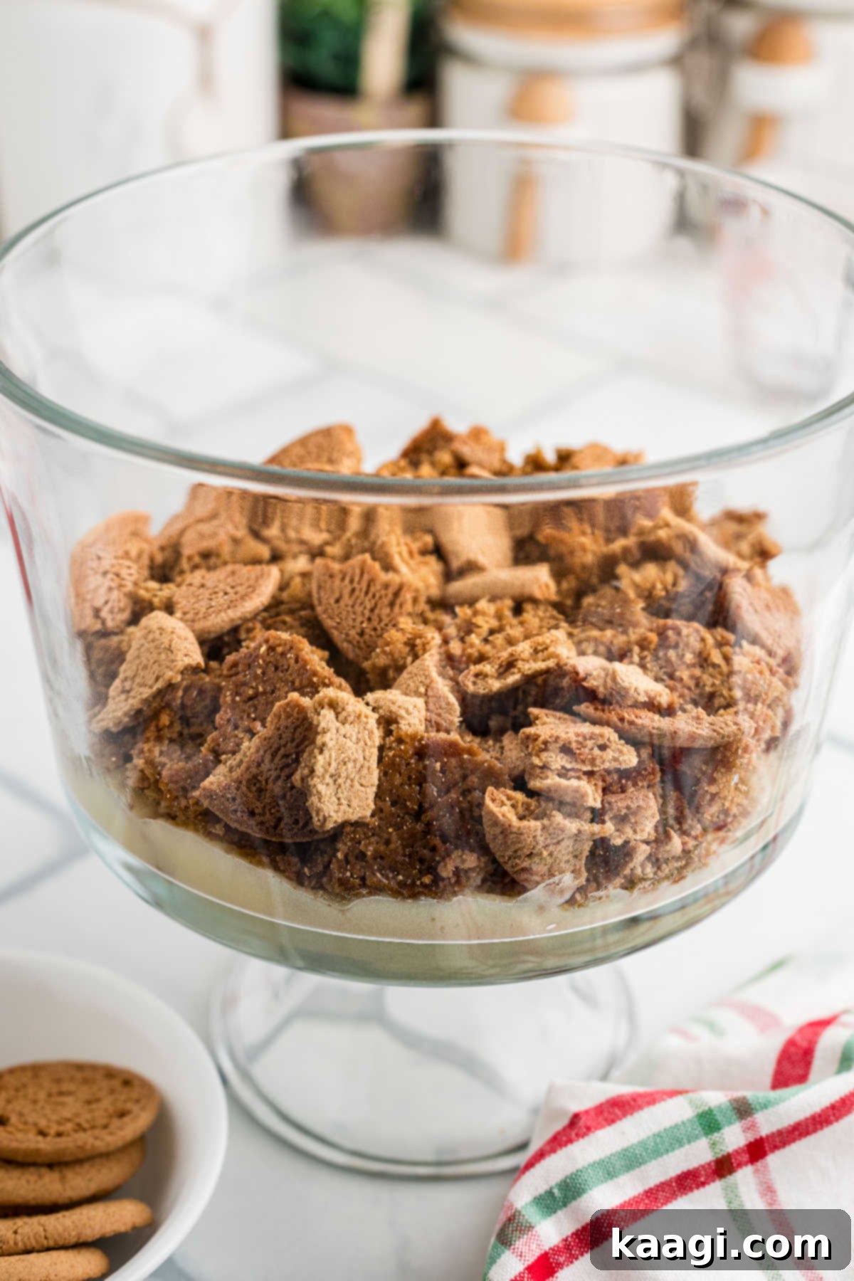 Festive Gingerbread Trifle 7 A trifle dish with a layer of pudding topped with cubes of gingerbread cake and crumbled gingersnap cookies.