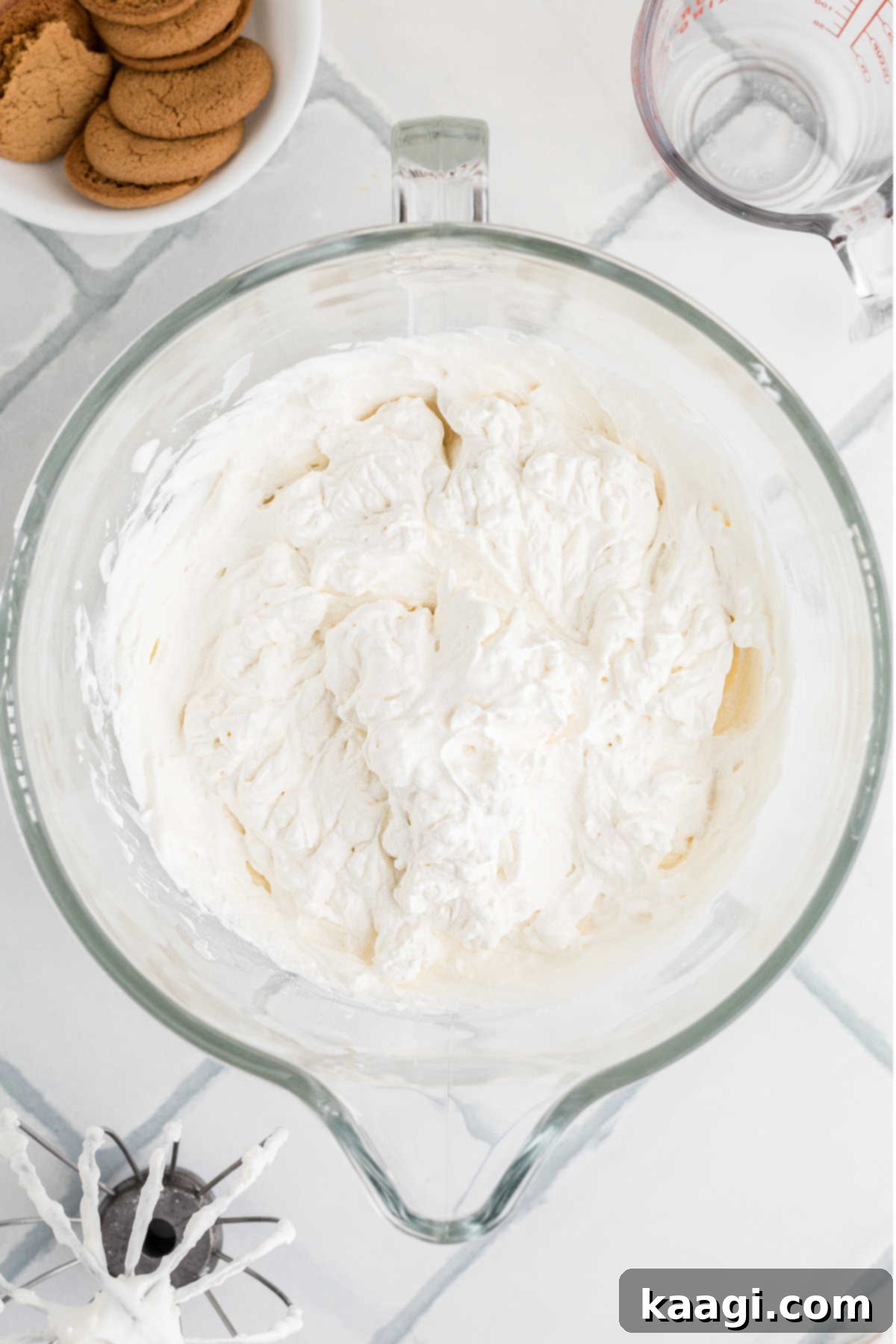 A large mixing bowl containing freshly whipped cream, showing stiff peaks.