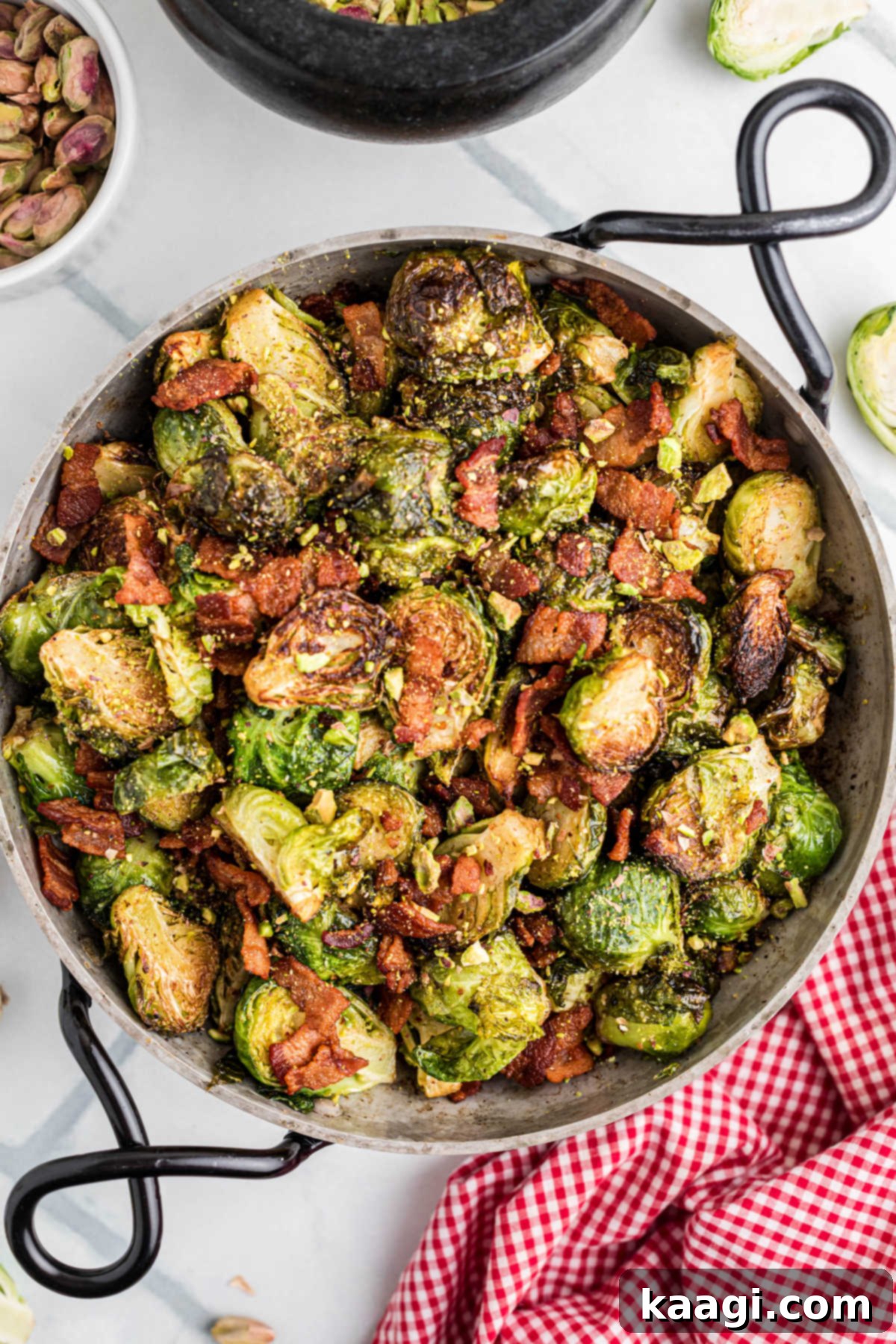 Sweet & Savory Maple Bacon Brussels Sprouts with Crunchy Pistachios 2 Overhead shot of a pan full of crispy maple bacon brussel sprouts with vibrant green pistachios sprinkled on top.