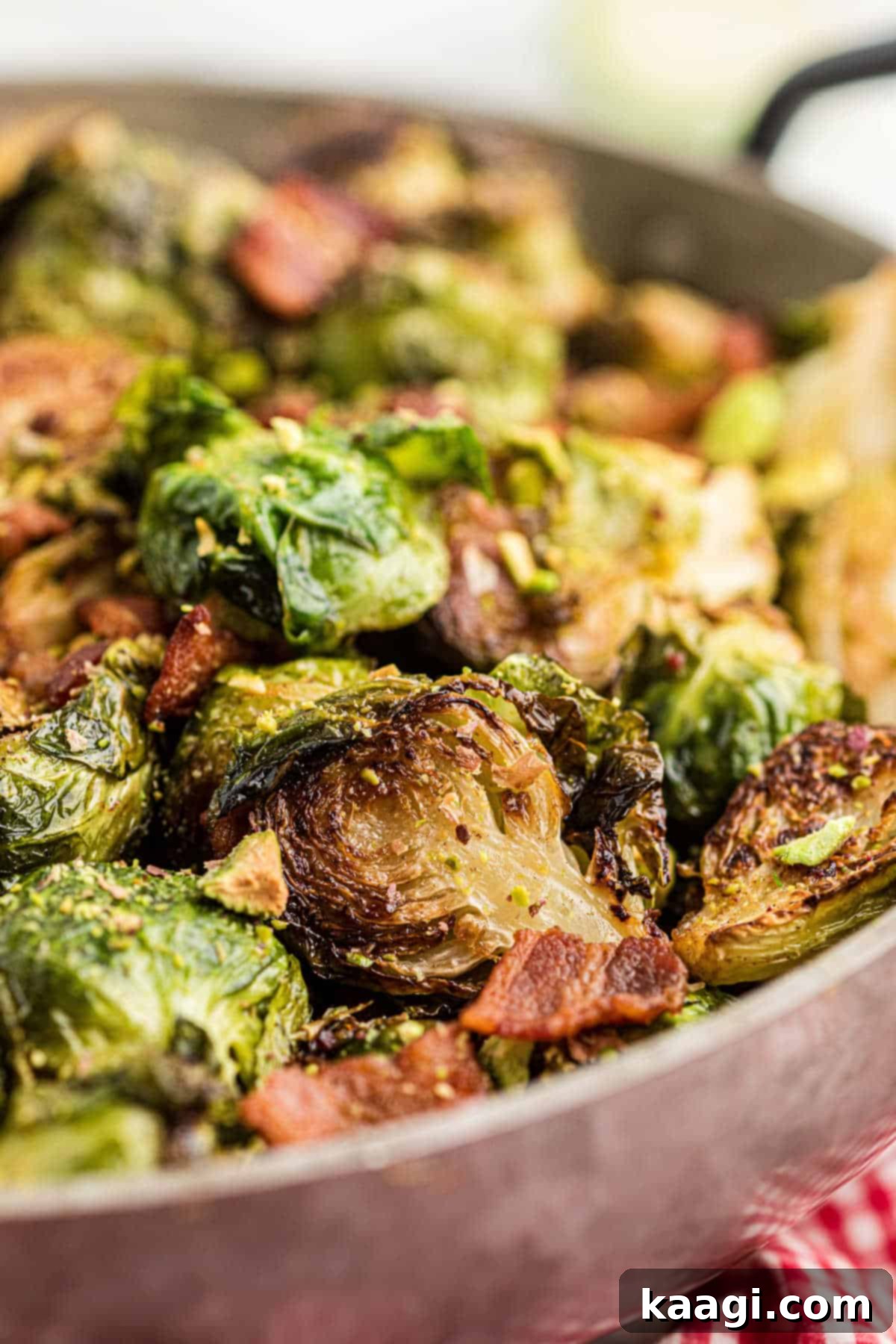 Sweet & Savory Maple Bacon Brussels Sprouts with Crunchy Pistachios 5 Close up of a pan full of perfectly cooked bacon brussel sprouts, showing crispy edges and rich color.