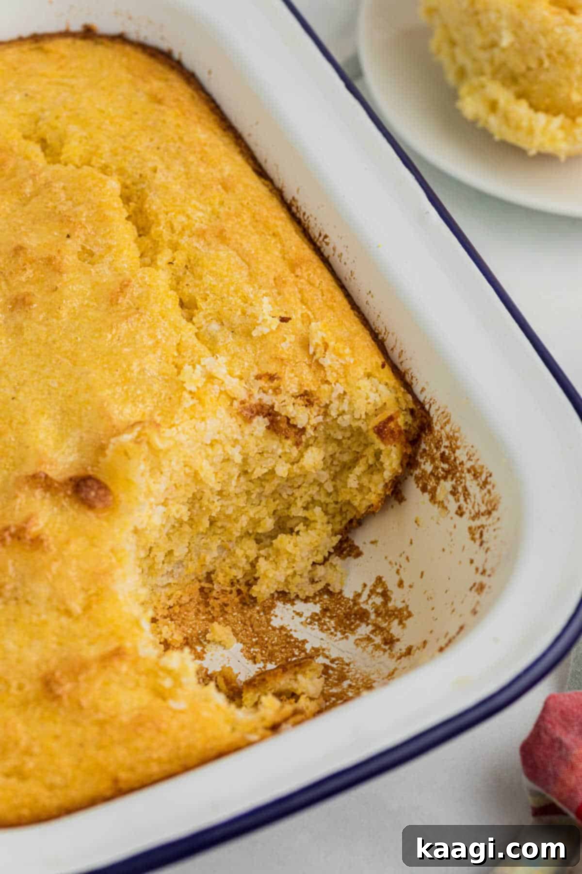 A pan with spoon bread, with a corner piece missing, showing the fluffy interior.