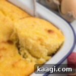 A corner of a piece of southern spoon bread being lifted out of the pan.