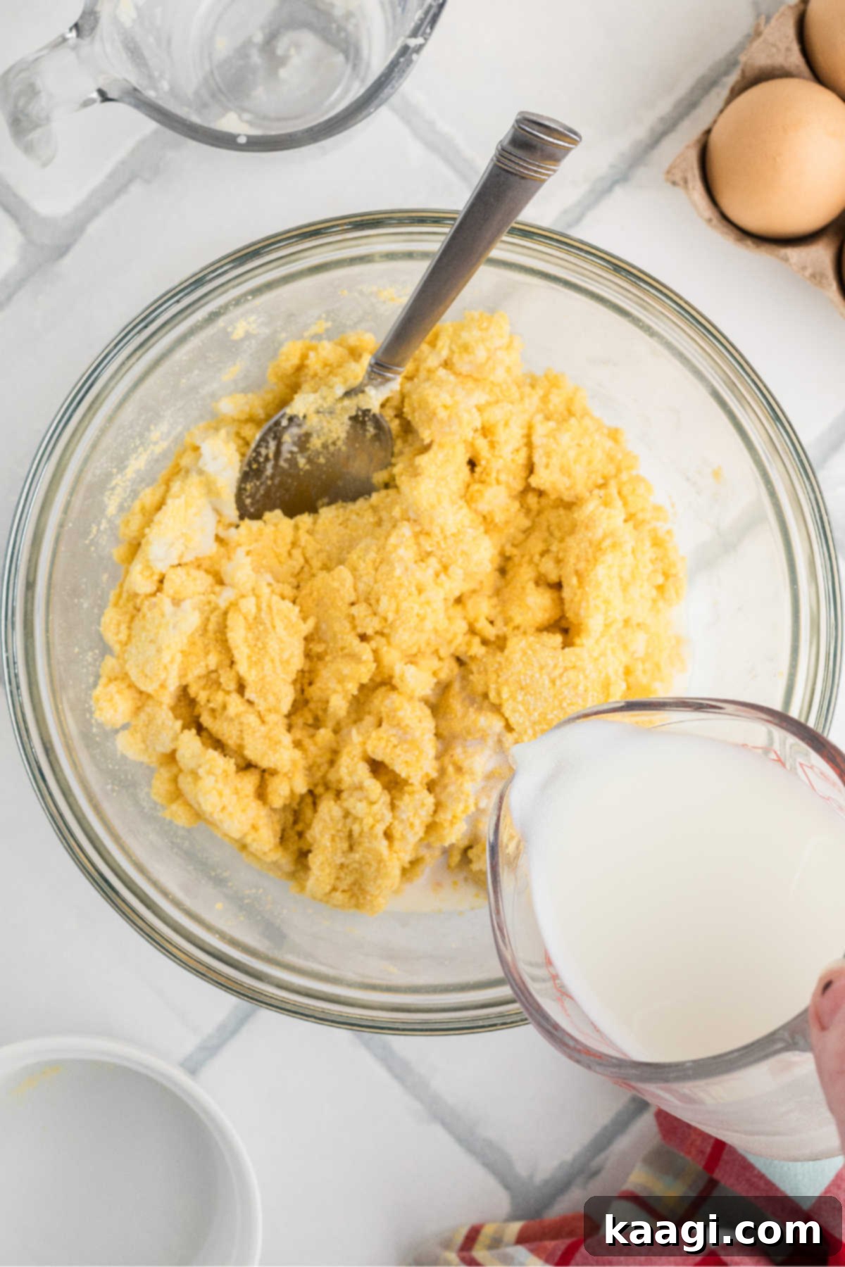 Milk being poured into spoon bread batter in a mixing bowl.