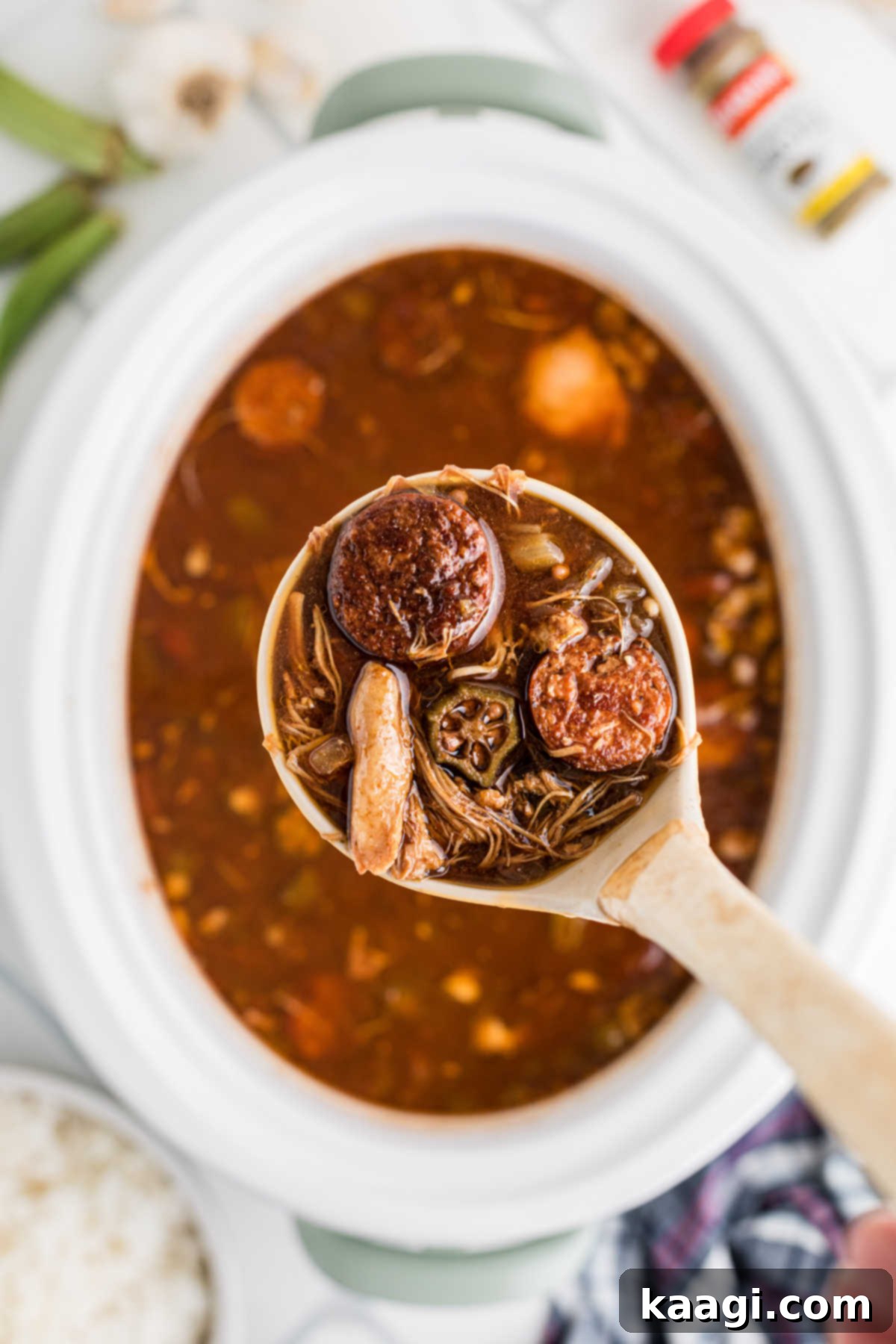 Slow Cooker Gumbo being spooned out with a ladle, showing its rich texture.
