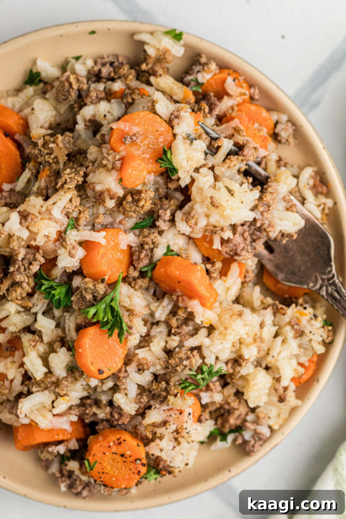 A serving dish filled with Crock Pot Carrots and Ground Meat, garnished with fresh herbs.