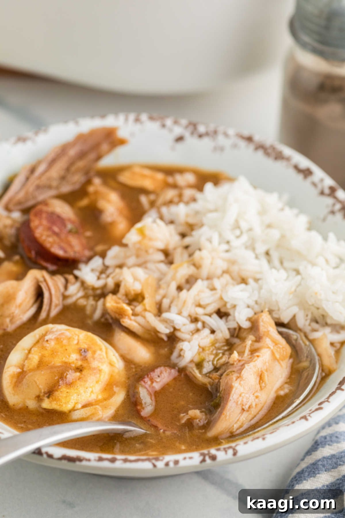 A steaming bowl of Leftover Turkey and Andouille Gumbo, garnished with fresh herbs and served with a spoon.