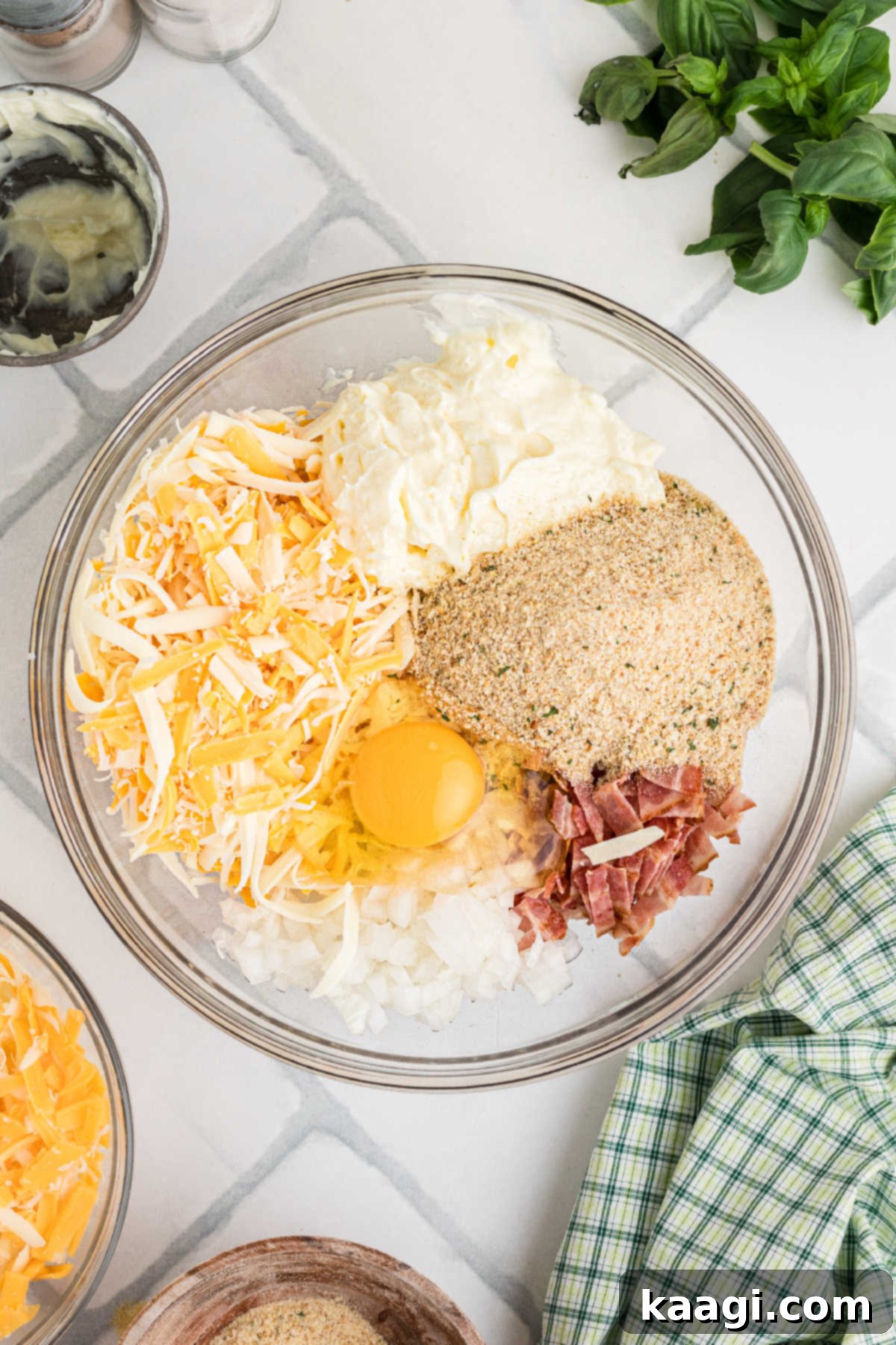 Dixie Tomato Tart 5 A large mixing bowl containing Italian breadcrumbs, a generous amount of grated mozzarella and sharp cheddar cheese, diced onions, and seasonings, ready to be combined.