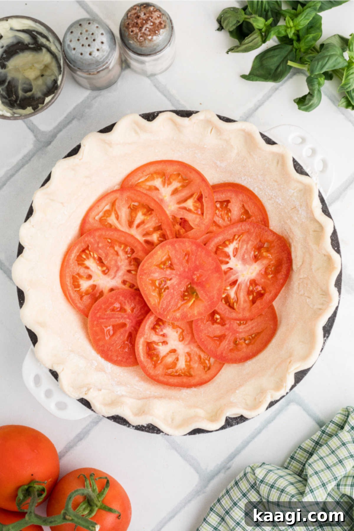 Dixie Tomato Tart 6 Perfectly sliced tomatoes being carefully layered into the bottom of a prepared pie crust, forming the first foundation of the pie.