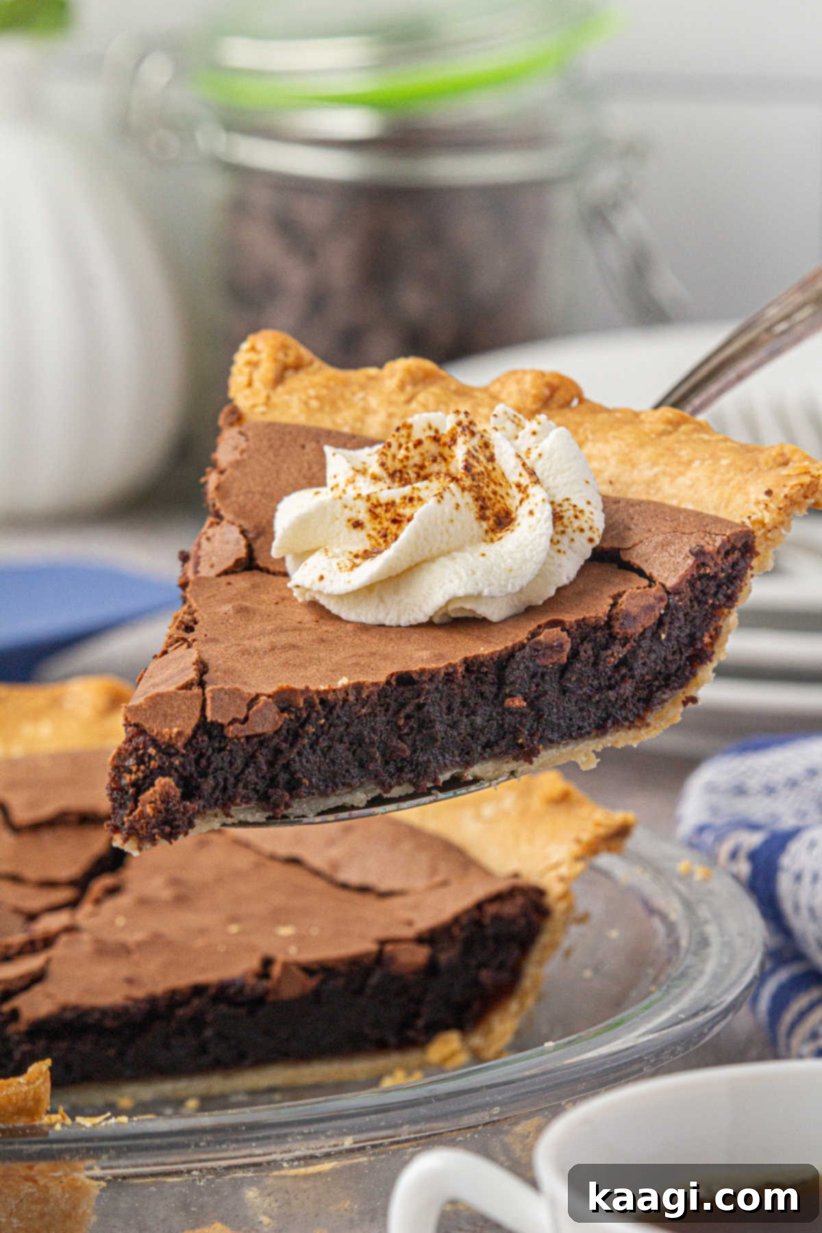 A slice of southern chocolate chess pie lifted out of pie dish with a squirt of cream on top, ready to be enjoyed.