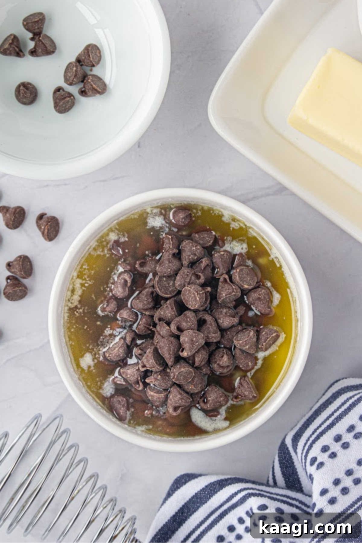 Chocolate chips and chunks of butter are placed in a small microwave-safe bowl, poised for melting.