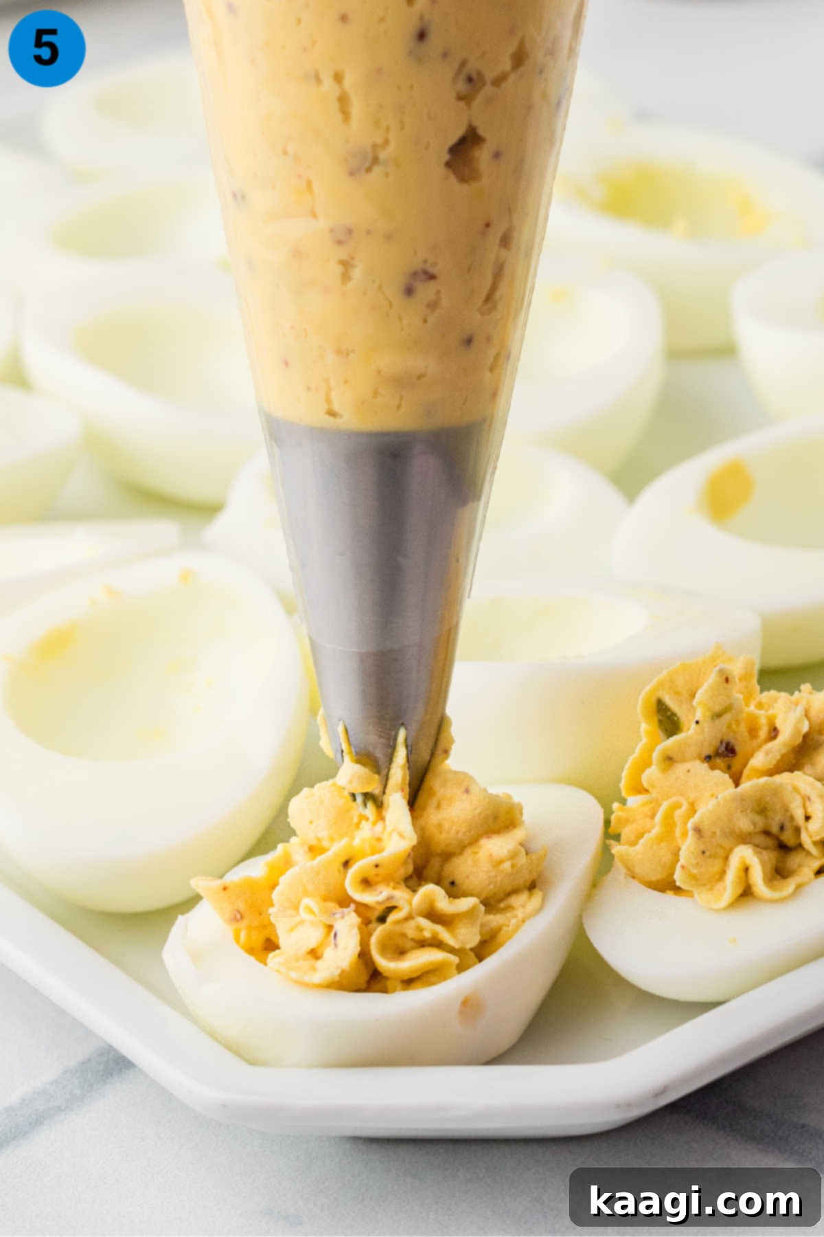 Fiery Cajun Deviled Eggs 5 Showing how to make Cajun deviled eggs, recipe step 5, piping the mixture into egg whites.