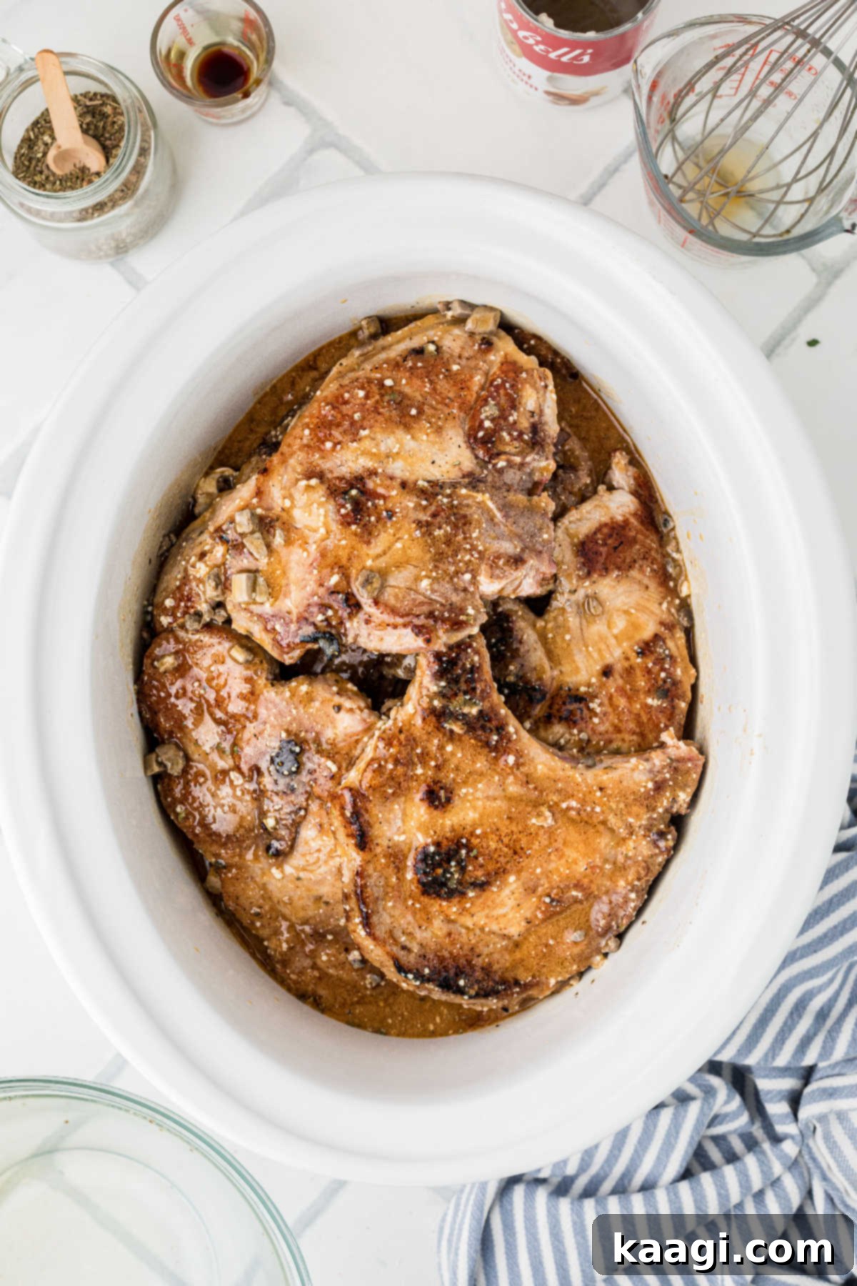 A slow cooker with pork chops and gravy, waiting to be cooked on low.