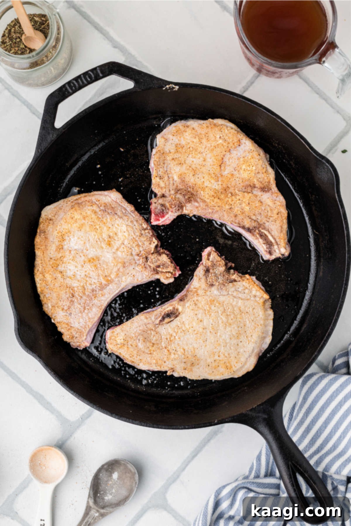 A cast iron skillet cooking some pork chops.