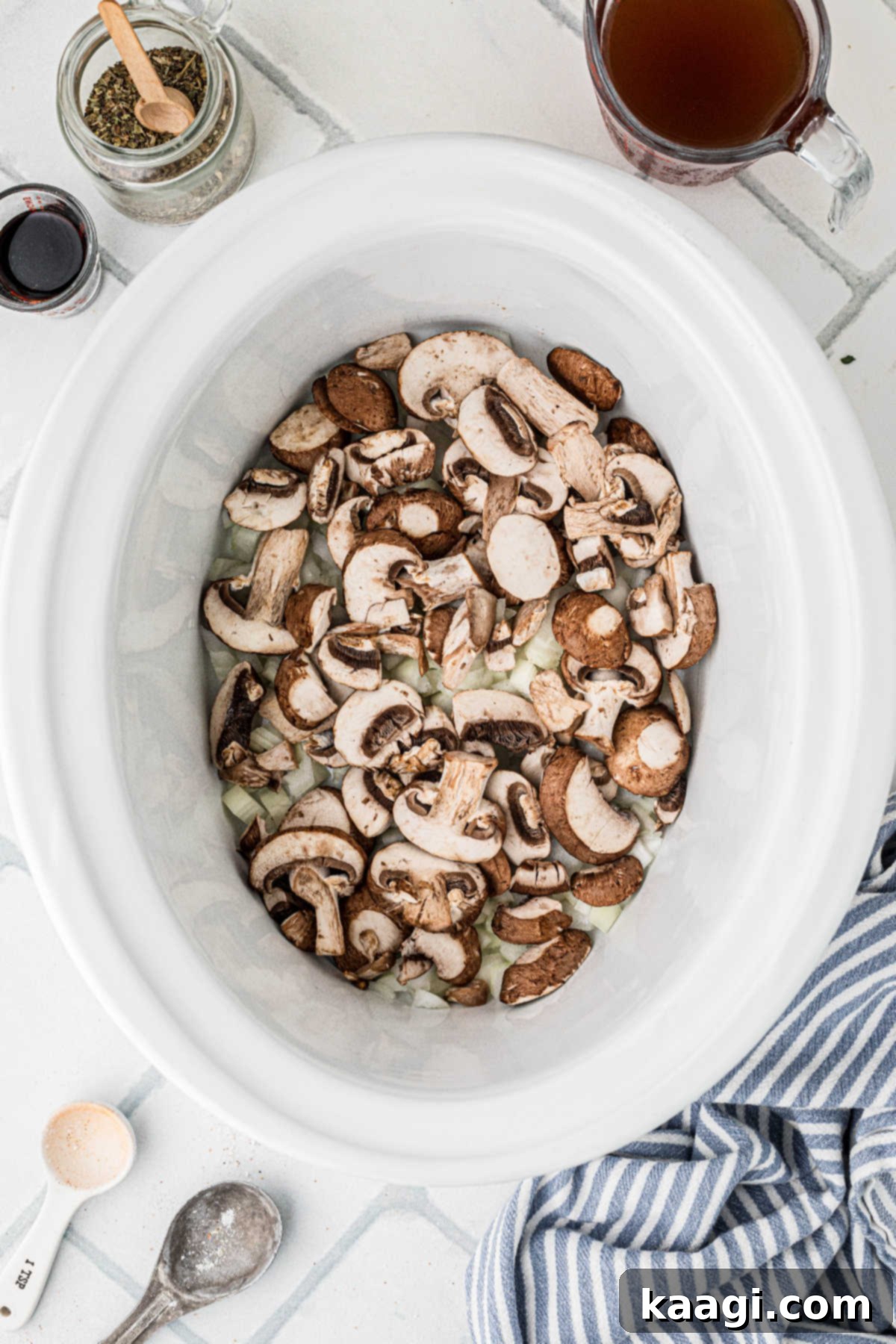 A large slow cooker filled with onions and mushrooms.