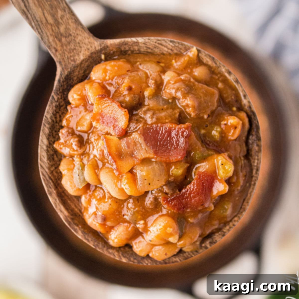 Elevate Your Plate with Essential Southern Sides 23 A close up of a spoon full of savory baked beans with crispy bacon, showcasing its rich texture and topping.